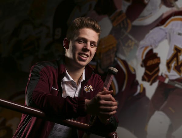 Gophers' junior defenseman Mike Reilly with the mural at Mariucci Arena where his image was added to the previous hockey All-America selections. ] JEF