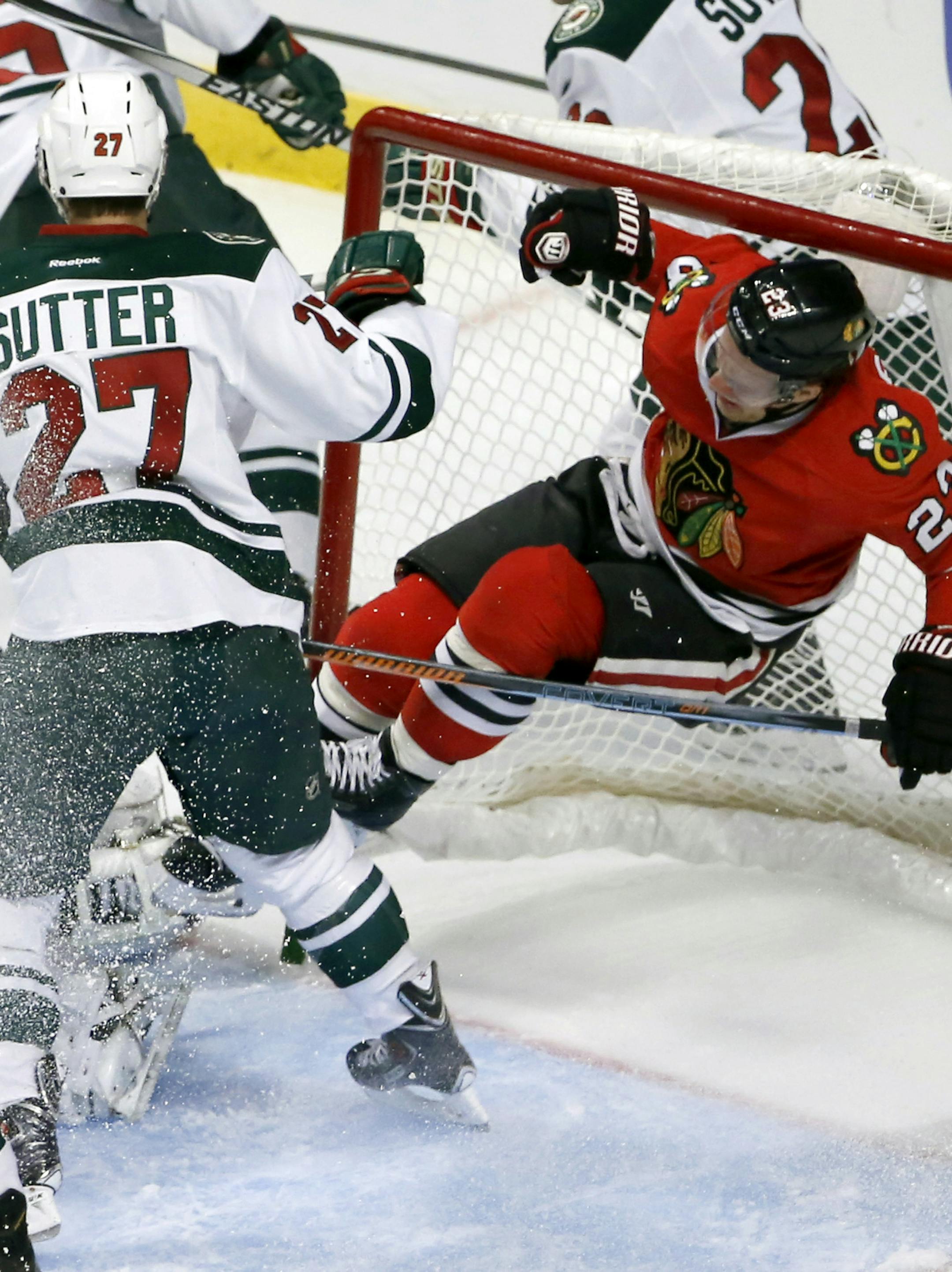 Minnesota Wild center Brett Sutter (27) pushes Chicago Blackhawks right wing Kris Versteeg (23) into the net, during a Blackhawks' power play during the second period of an NHL hockey game Tuesday, Dec. 16, 2014, in Chicago. (AP Photo/Charles Rex Arbogast)