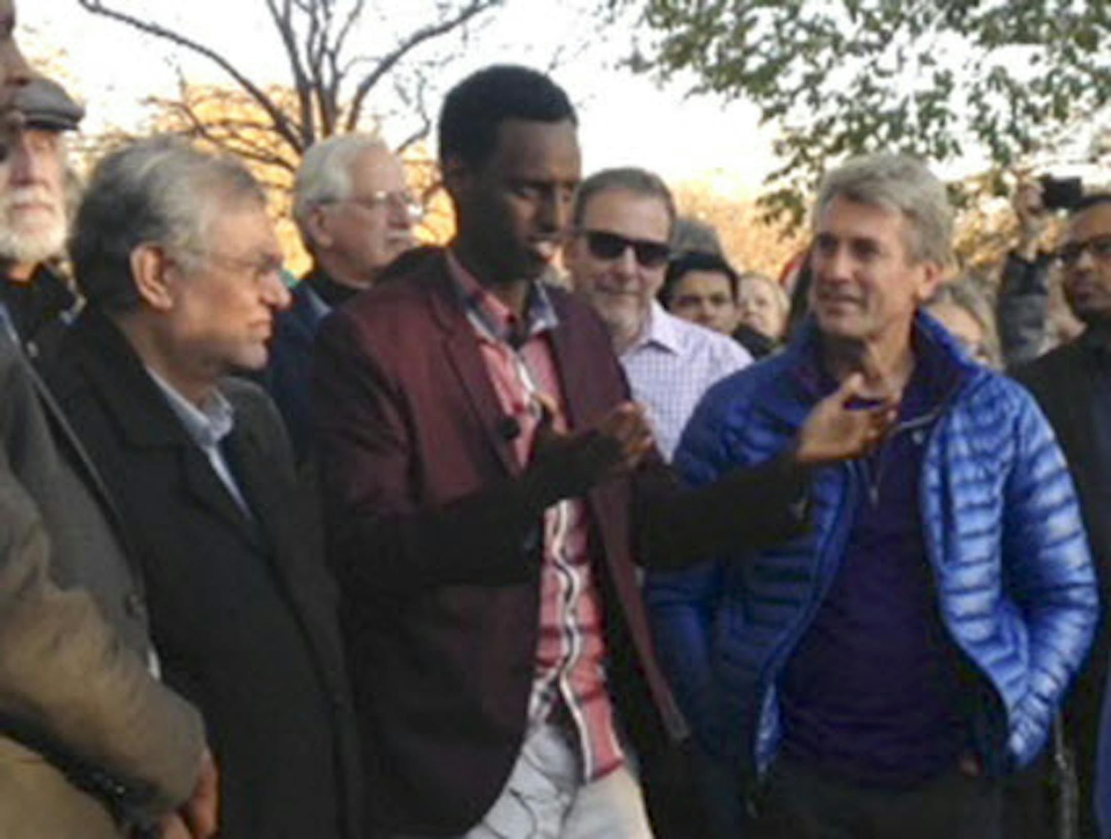 Hamse Warfa, with R.T. Rybak, right, speaks to a television crew about Sambusa Sundayís message of unity and thanks.