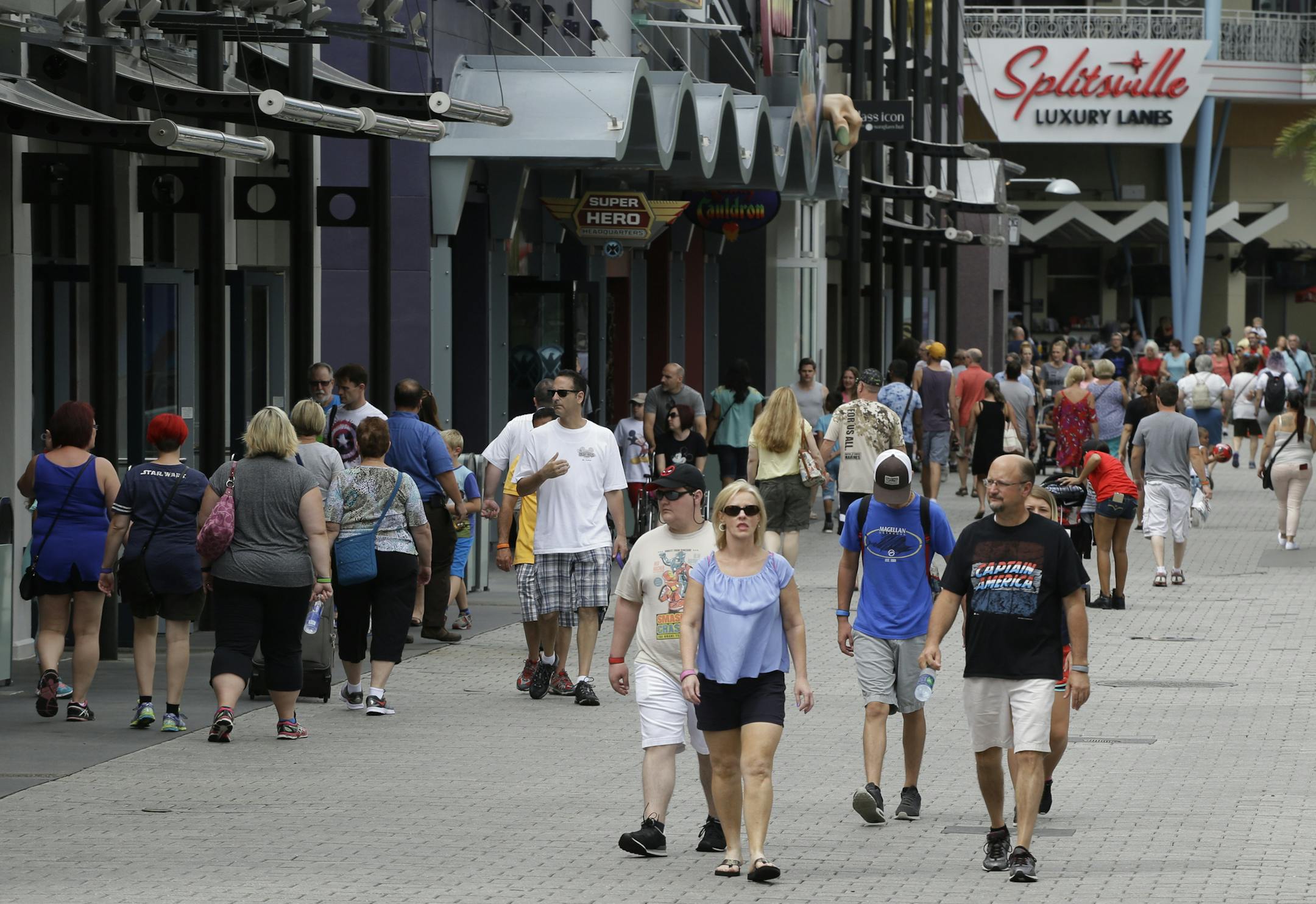 In this Tuesday, Sept. 13, 2016 photo, tourists stroll by the shops and restaurants at the Disney Spring complex in Lake Buena Vista, Fla. Hotel occupancy rates in the Orlando area are down about 2.5 percent for the year through July. (AP Photo/John Raoux)