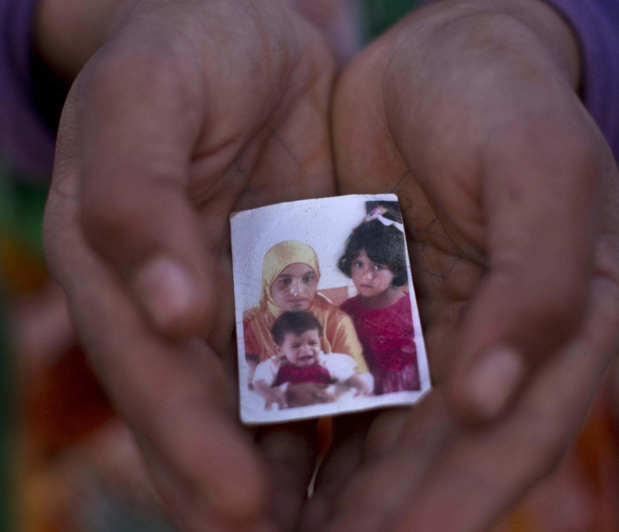 In this Wednesday, July 22, 2015 photo, Syrian refugee Hannan Mohammed, 12, holds a picture of herself and her sister Warda, 5, and the youngest Jawahir, 1, who died last February after suffering from chronic malnutrition, outside their tent at an informal tented settlement near the Syrian border on the outskirts of Mafraq, Jordan. Of the 4 million refugees who fled Syria’s grinding civil war, it is the conflict’s youngest exiles, like Jawahir, who often bear the brunt of its woes.