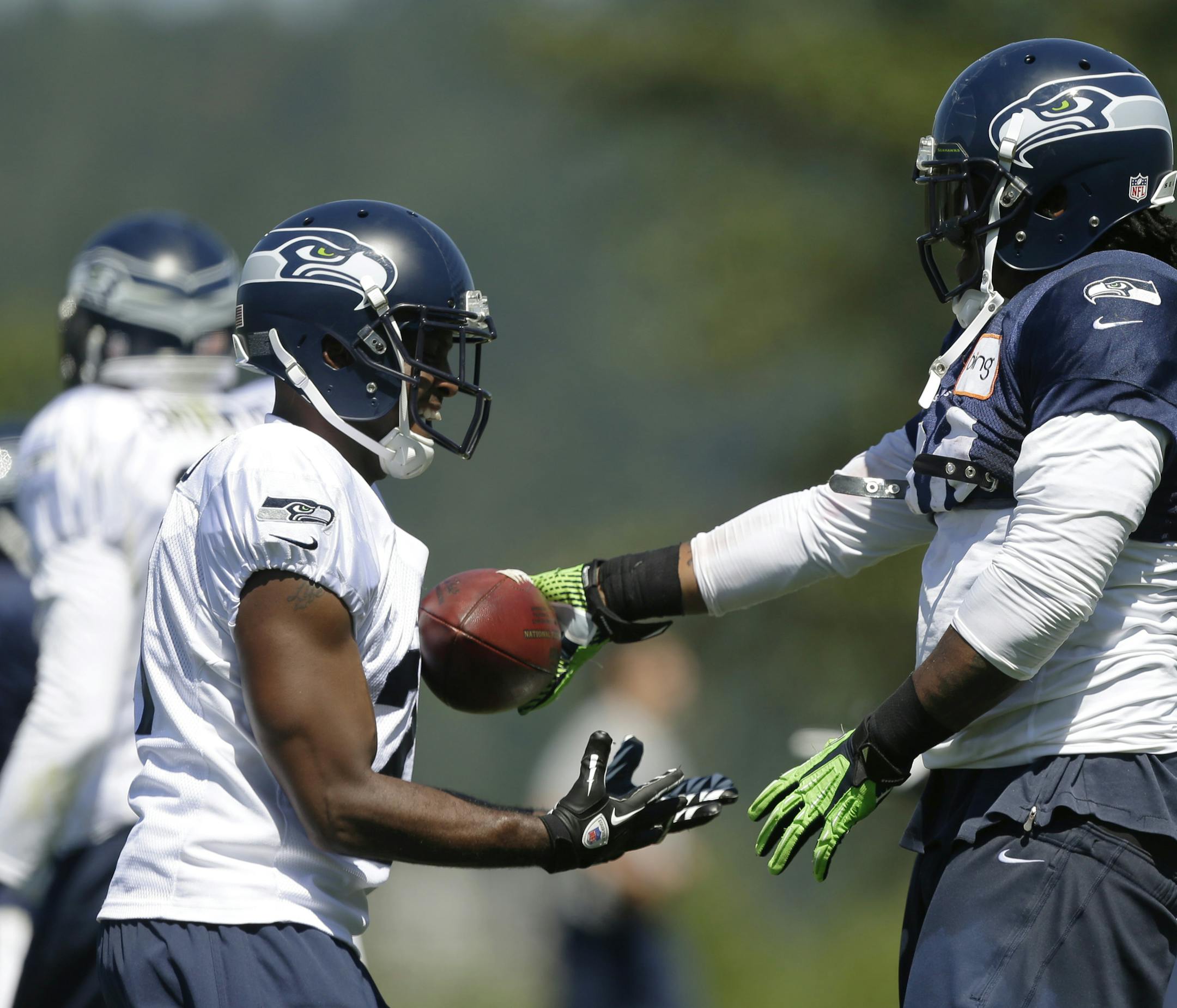 Seattle Seahawks running back Marshawn Lynch, right, playfully gives the ball to cornerback Antoine Winfield, left, after Lynch made a run during NFL football training camp, Saturday, July 27, 2013, in Renton, Wash. (AP Photo/Ted S. Warren) ORG XMIT: MIN2013080416470831