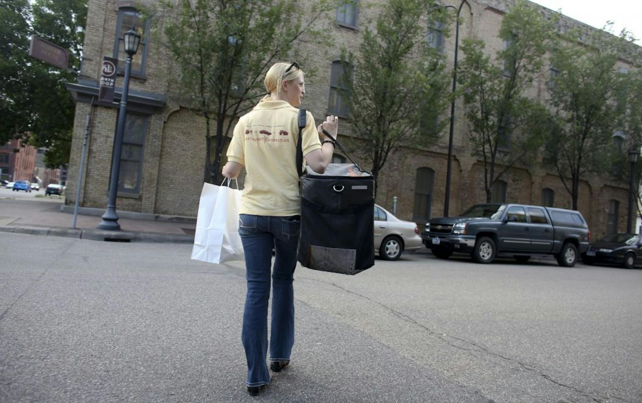 Keli Gilbertson, general manager for Restaurant Connection, headed back to her car with an order from Origami in Minneapolis, Min., Tuesday, July 24, 2012. Restaurant Connection, San Diego-based company provides more than 30 Twin Cities restaurants with home delivery service.