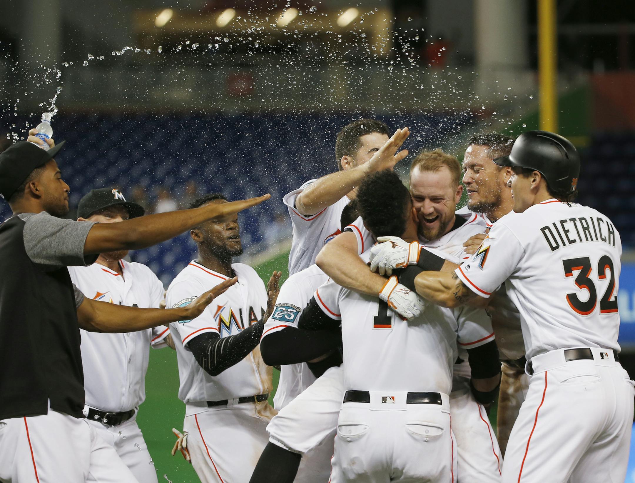 Miami Marlins catcher Bryan Holaday, third from right, is picked up by Starlin Castro as he is mobbed by teammates after Holiday hit a single scoring Miguel Rojas for the win during the 10th inning of a baseball game against the Milwaukee Brewers, Monday, July 9, 2018, in Miami. The Marlins defeated the Brewers 4-3 in 10 innings. (AP Photo/Wilfredo Lee)