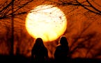 People watch the sunset at a park on an unseasonably warm day, Feb. 25, 2024, in Kansas City, Mo. Climate change is making giant heat waves crawl slow