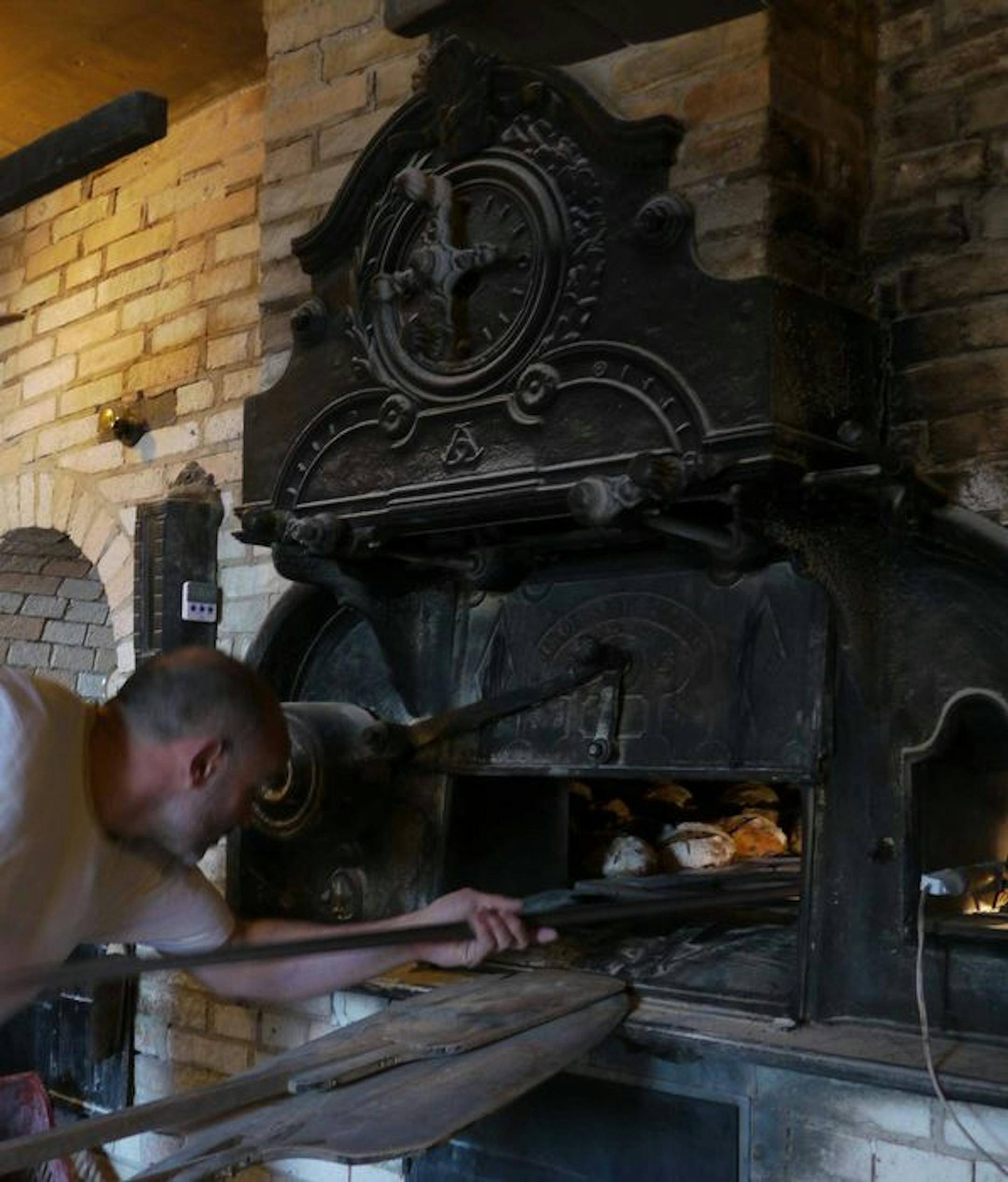 Laurent Pouget puts loaves of sourdough bread into the 10- by 13-foot vaulted wood-burning oven.