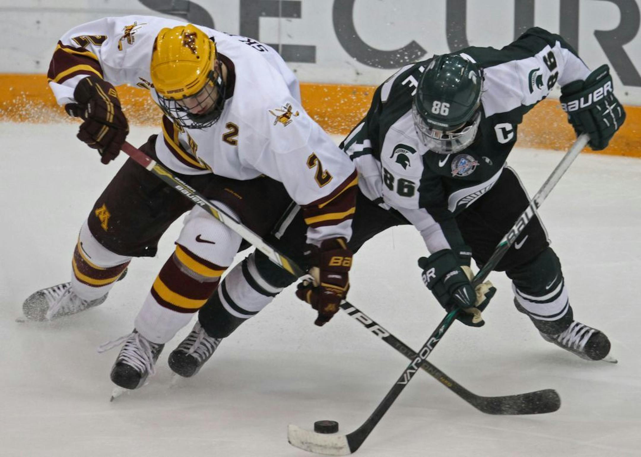 Minnesota's Brady Skjei and Michigan State's Greg Wolfe battled for the puck.