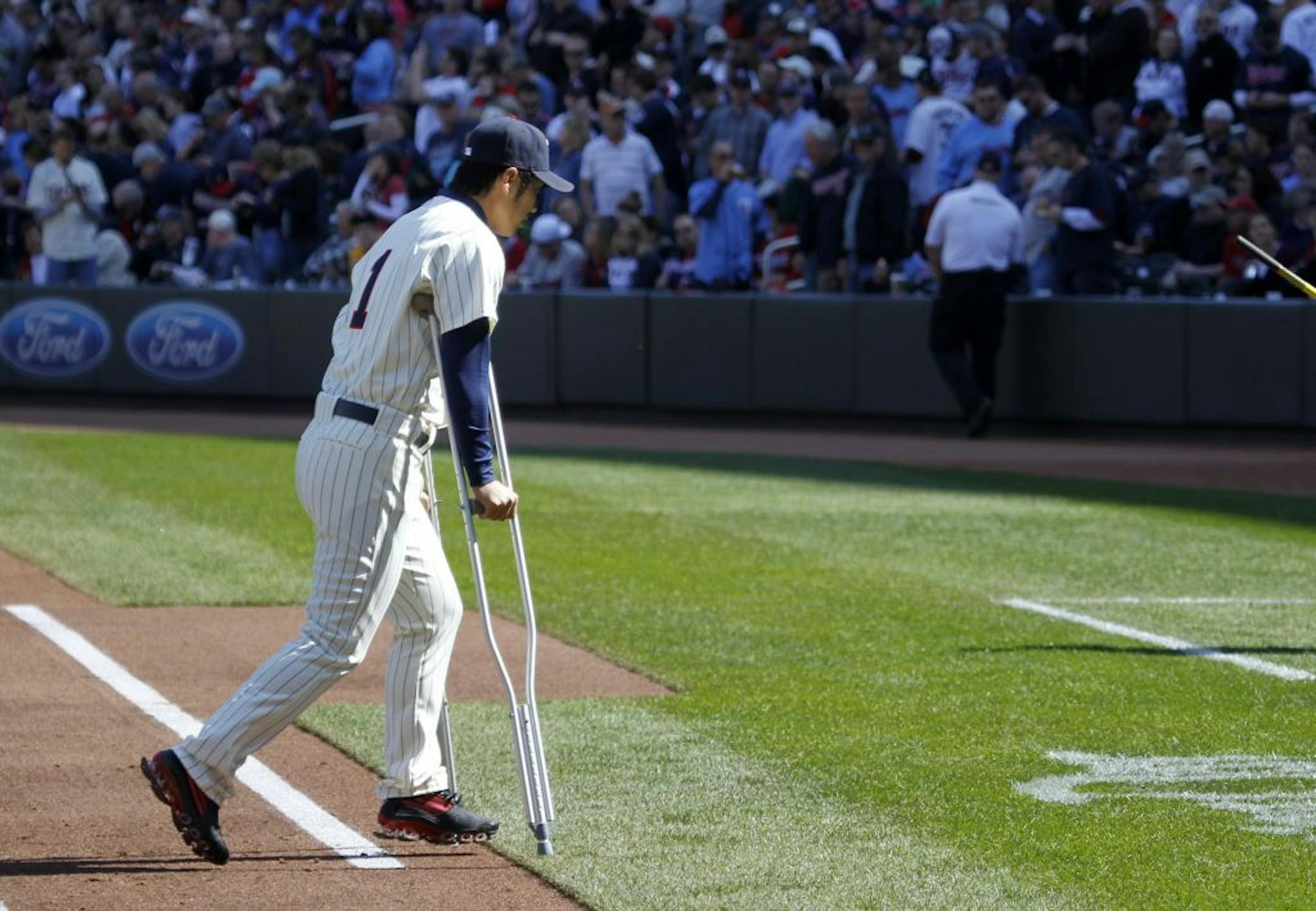 TWINS -vs- OAKLAND OPENING DAY - ] Twins short stop Tsuyoshi Nishioka walks off the field with crutches after team introductions. Nishioka broke his leg Sunday in a game against the Yankees