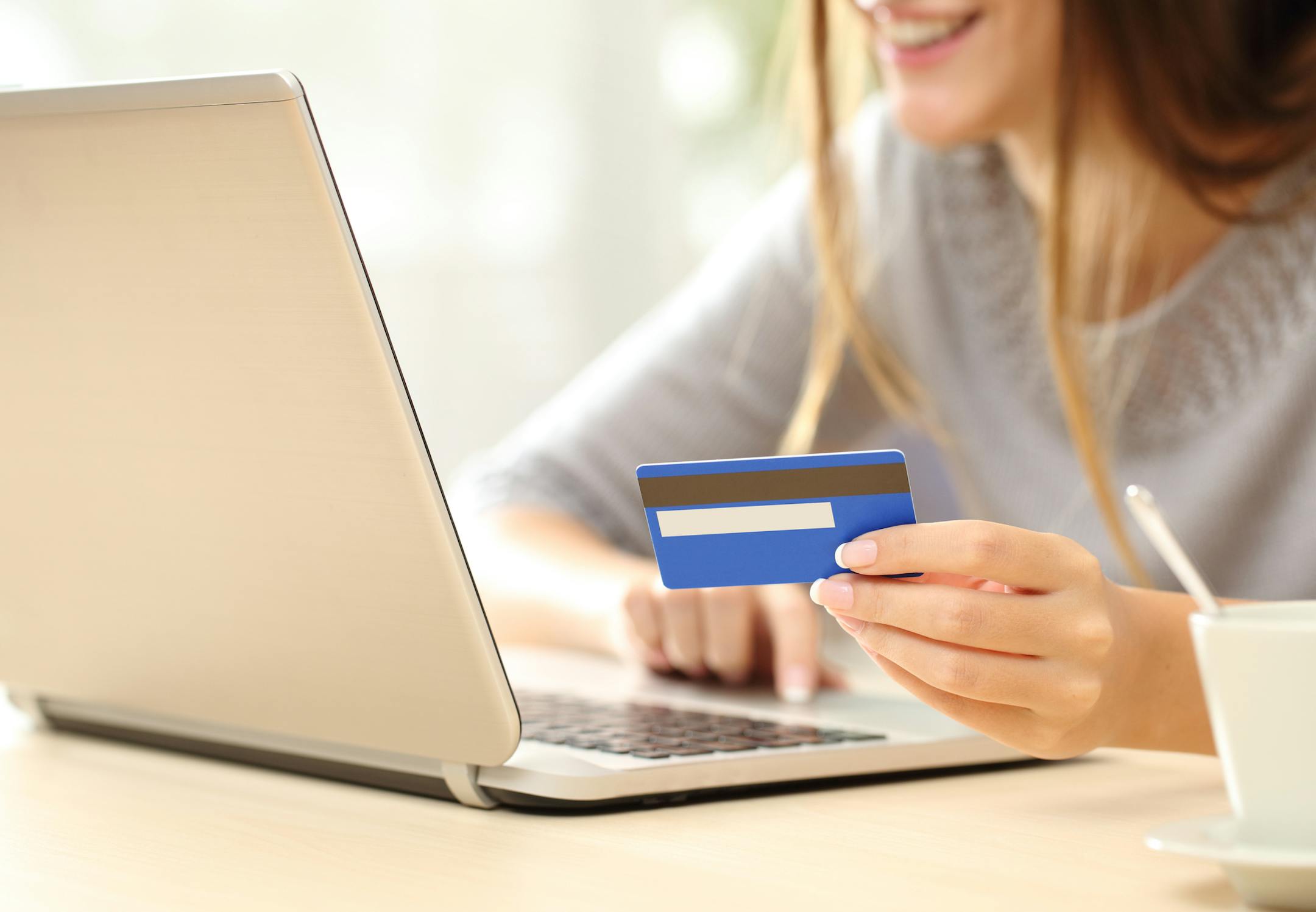 Close up of a happy woman hand buying online with a laptop and paying with a credit card