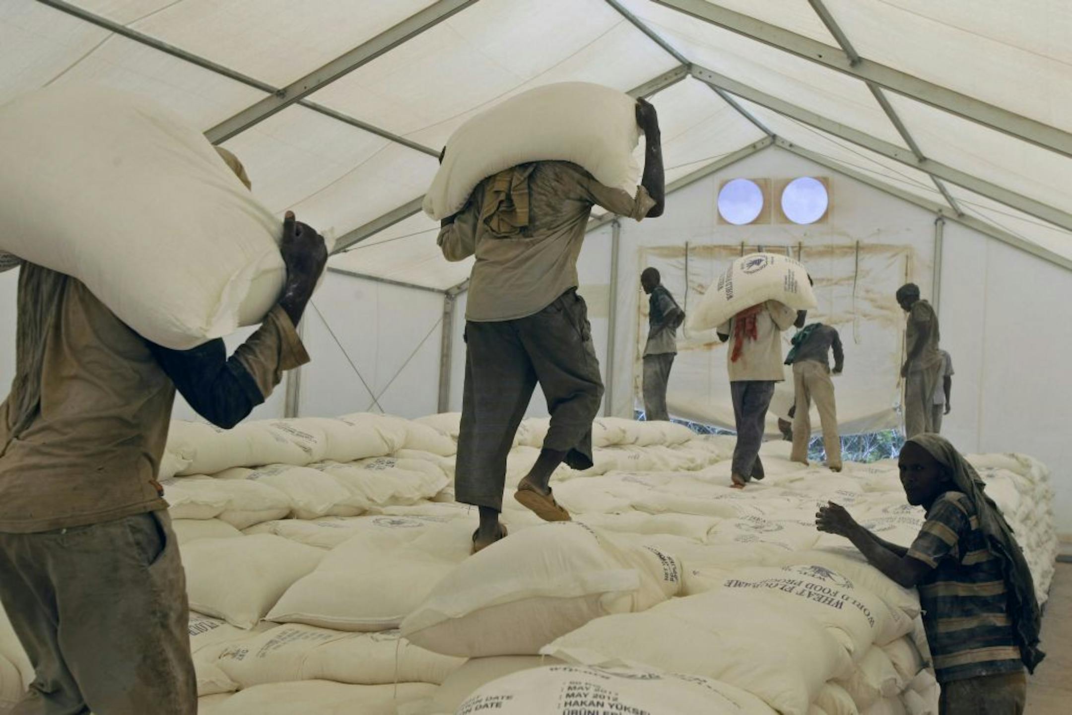 Workers carried sacks of food at a distribution center in Dadaab, Kenya, on Tuesday. Dadaab, a camp designed for 90,000 people, now houses about 440,000 refugees. Almost all are from Somalia, with more than 1,000 arriving daily as they flee fighting or hunger.
