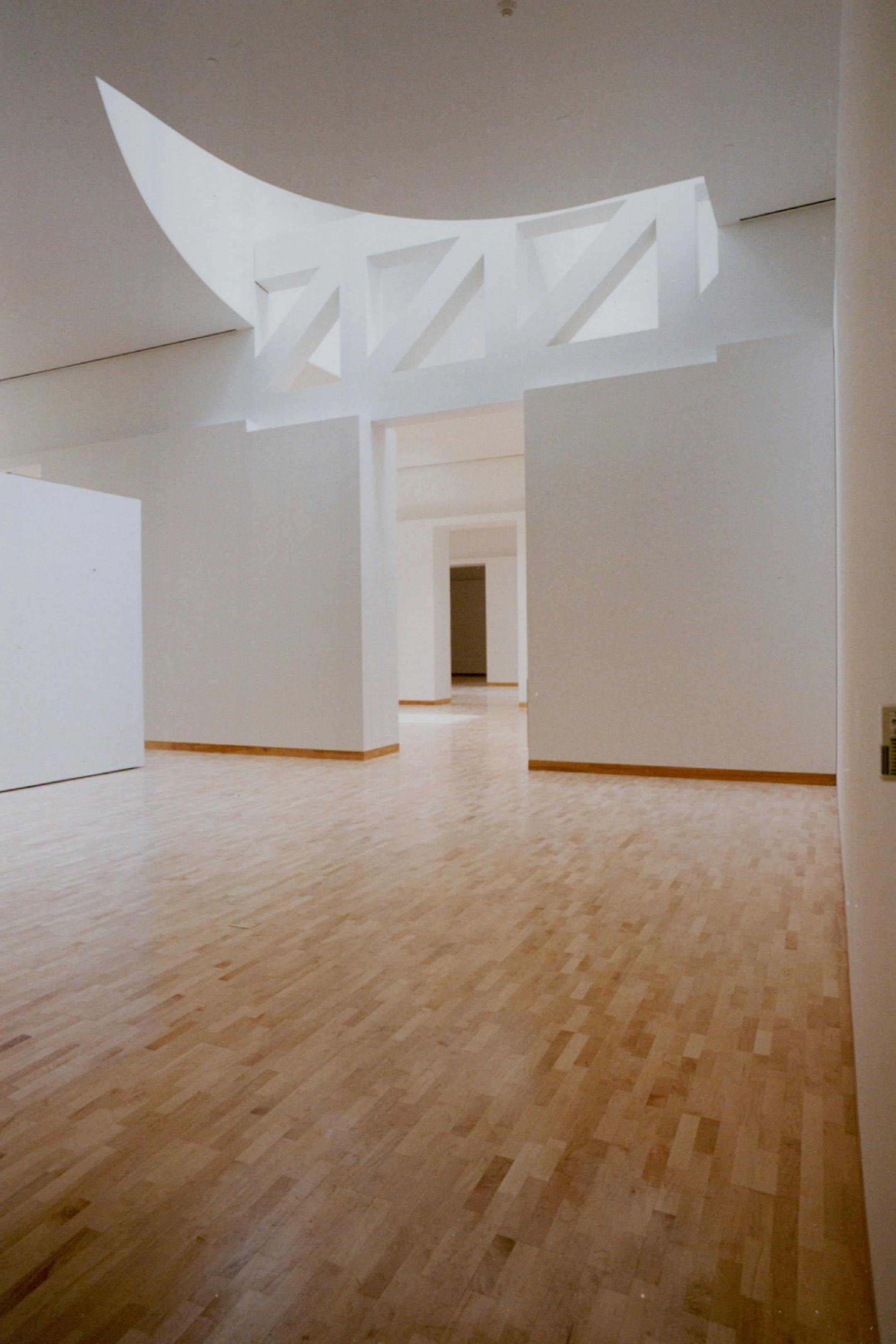 July 19, 1993 The arresting exterior of the Frederick R. Weisman Art Museum, top, at the University of Minnesota makes a glittering foil for the serene interior spaces. Left, a free-standing divider splashed with sunlight separates two gallery spaces. Below, a free-shaped skylight cove and geometric support the girder add to the idiosyncratic gallery shapes. July 1, 1993 Jeff Wheeler, Minneapolis Star Tribune