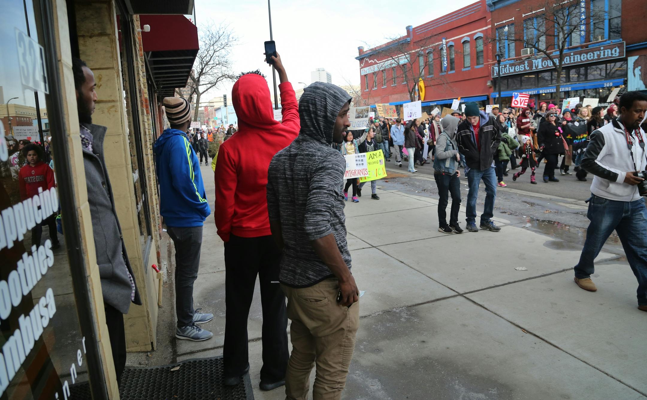 Young men emerge from the West Bank Cafe in Cedar-Riverside to see to check out The Caravan of Love: A Walk of Love for Immigrants and Refugees.