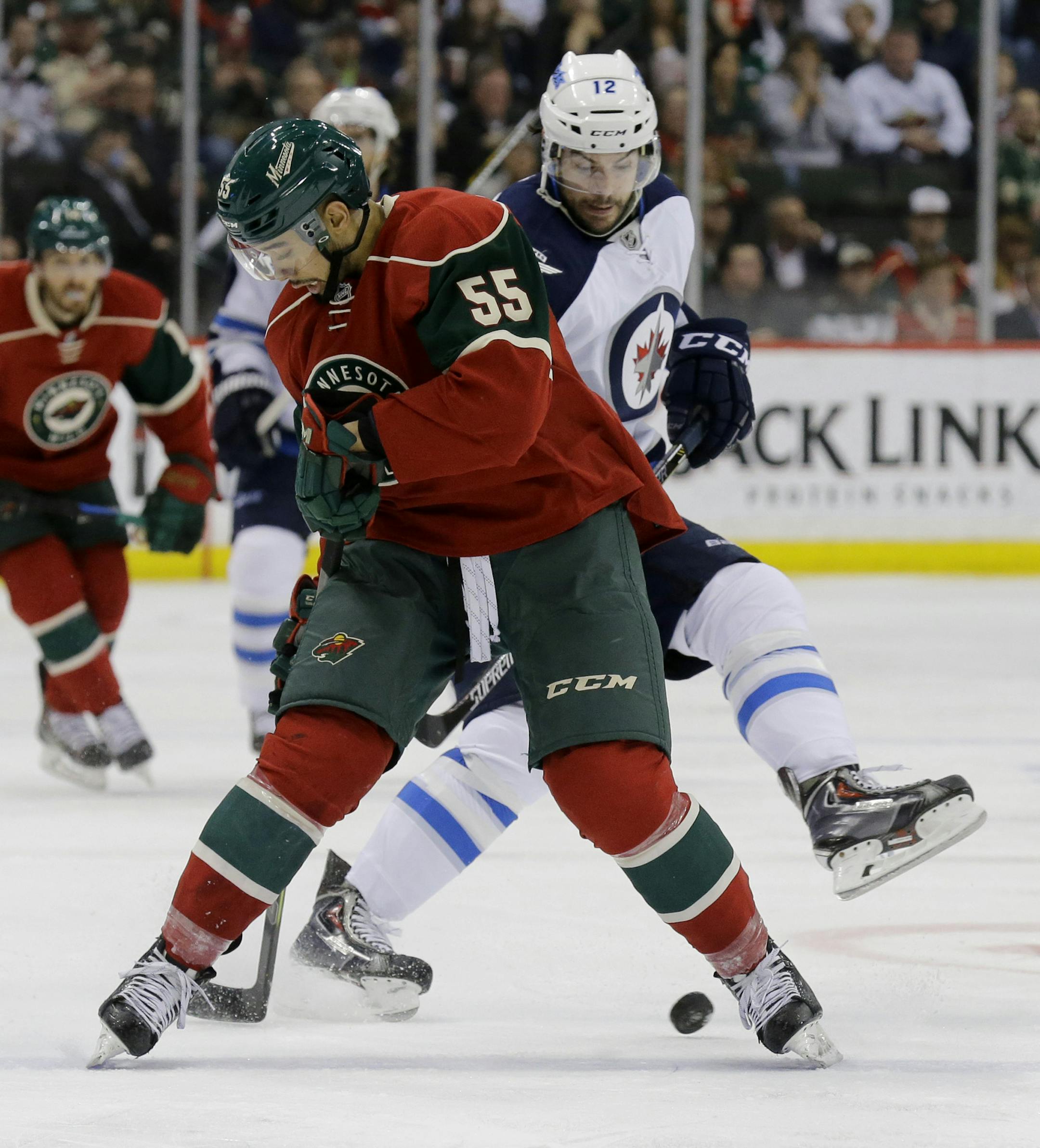 Minnesota Wild defenseman Matt Dumba (55) and Winnipeg Jets right wing Drew Stafford (12) battle for the puck during the second period of an NHL hockey game in St. Paul, Minn., Monday, April 6, 2015. (AP Photo/Ann Heisenfelt) ORG XMIT: MIN2015041620504950