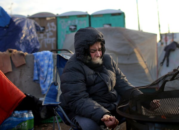 Angie Morrow, 40, warms her hands by a fire at the Hiawatha homeless encampment Tuesday, Nov. 13, 2018, in Minneapolis, MN. Morrow has been living on 