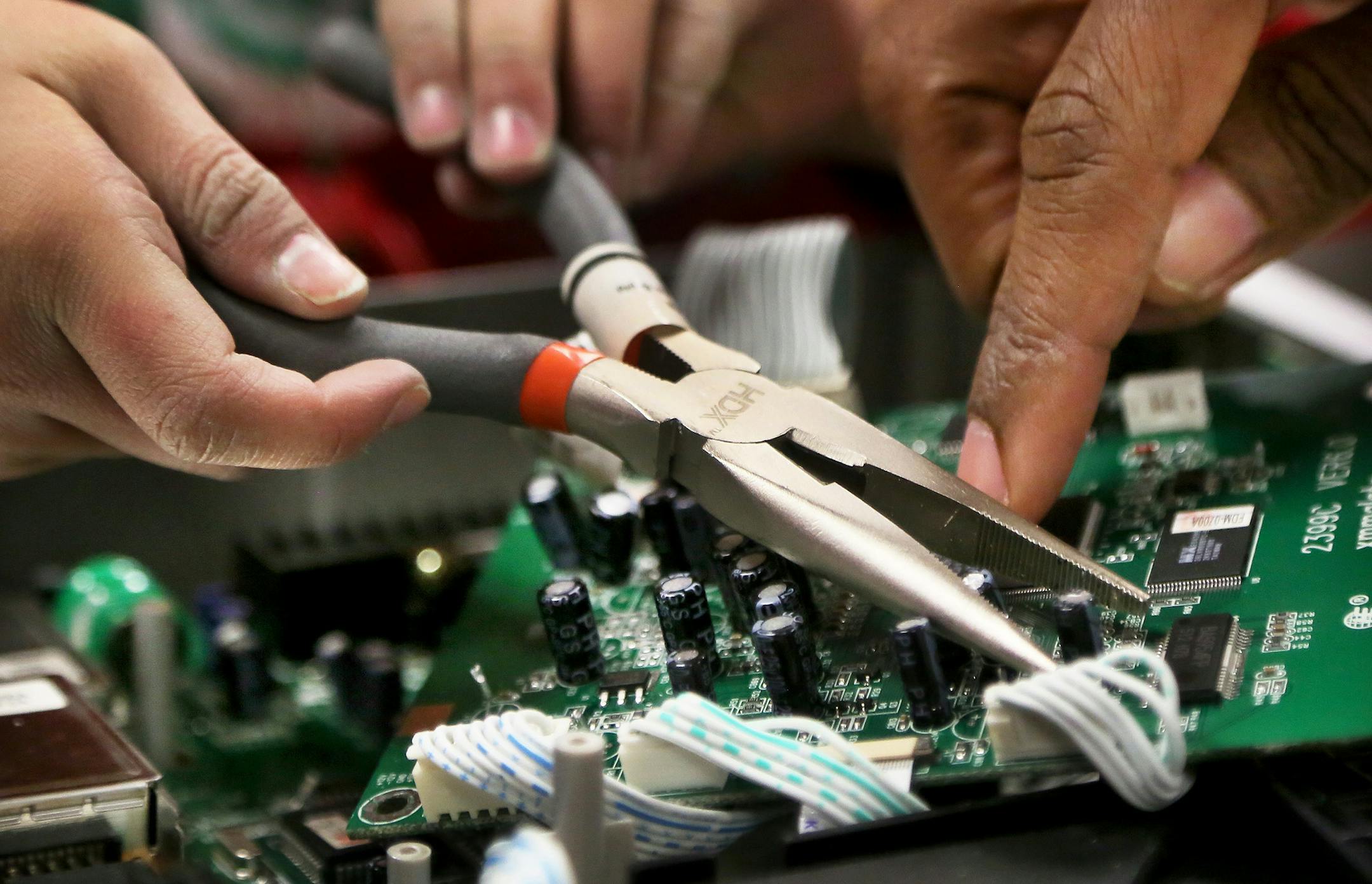 The Works Museum exploded with activity during the annual celebration of National Engineers Week Saturday, Feb. 28, 2015, in Bloomington, MN. Here, Caroline Fairbrother, 6, left, and her brother Lucas, 3, not pictured, did some reverse engineering on a DVD player with the help of volunteer Ted Williams, an engineer for Xcel Energy, right. Caroline and Lucas used pliers to remove capacitors and circuits from the player. "This whole entire city," Caroline said, referring to the numerous parts in t