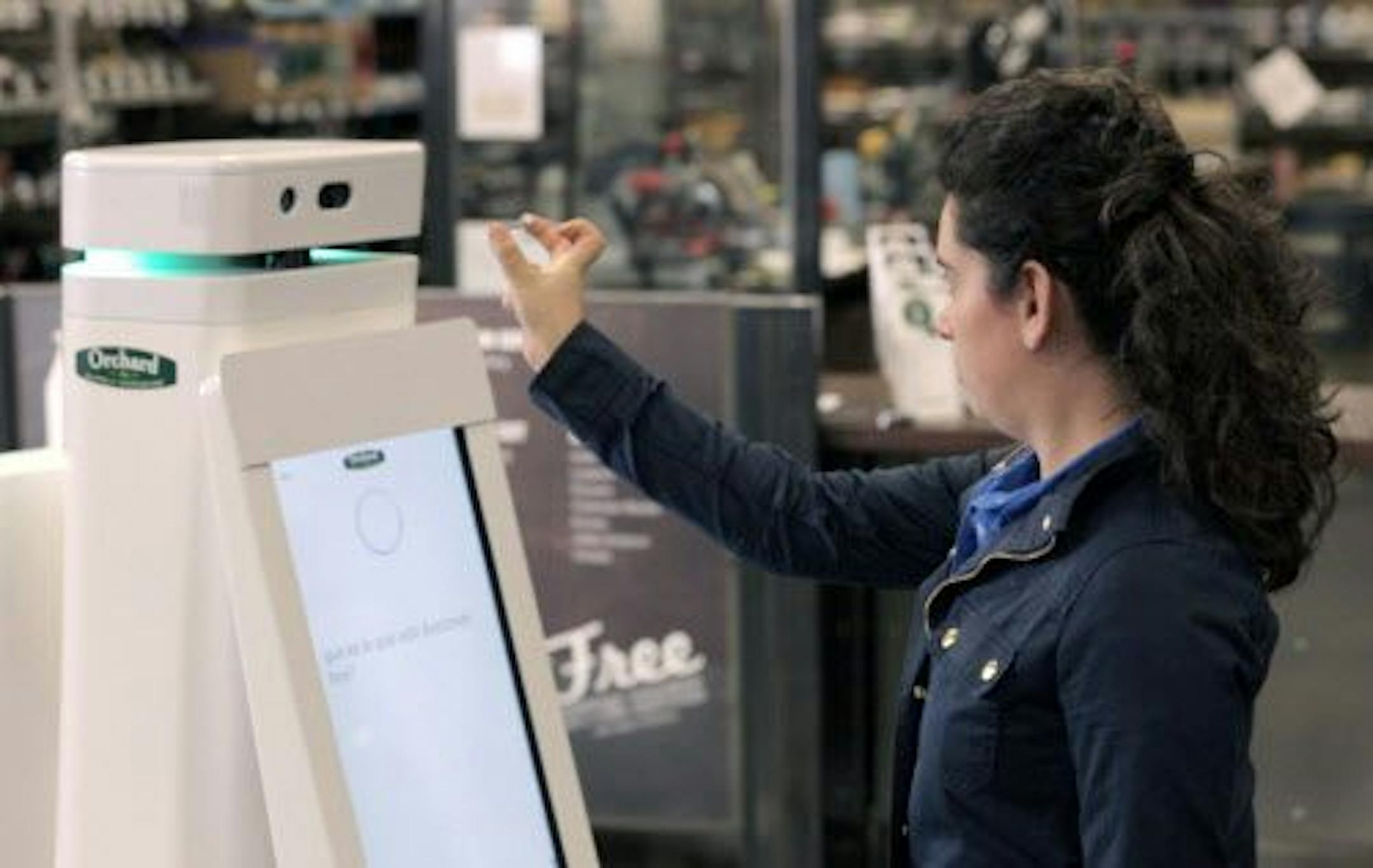 In this undated image provided by Lowe's, a woman holds a nail up to be scanned by an OSHbot robot.