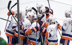 New York Islanders center Brock Nelson (29) is surrounded by teammates after he scored the wining goal in overtime of an NHL hockey game against the M