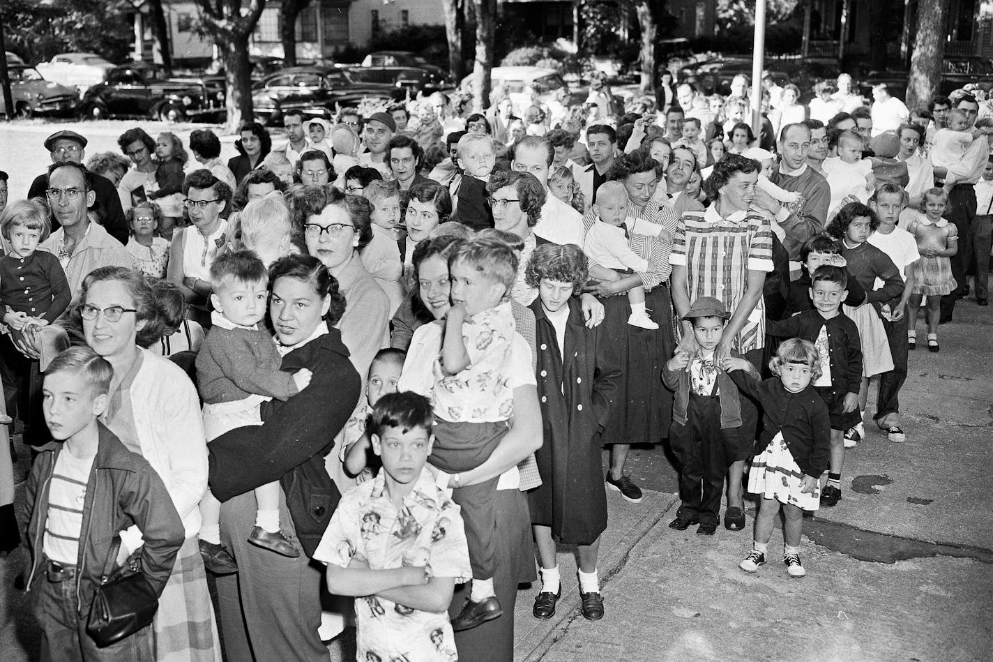 FILE - Parents and children wait outside the Riverside Public School in Elmira, N.Y., on July 1, 1953, to get the polio vaccine, due to the rise in infantile paralysis in Chemung and Steuben Counties. The Centers for Disease Control and Prevention said the polio virus was detected in wastewater samples collected in June 2022 from Rockland County outside New York City. An unvaccinated adult recently contracted the life-threatening disease, but health officials said Tuesday, Aug. 2, 2022, they have not identified additional cases. (AP Photo/Paul E. Thomson, File)