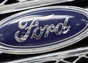 FILE - In this Monday, Jan. 5, 2015, file photo, the Ford logo shines on the front grille of a 2014 Ford F-150, on display at a local dealership in Hi