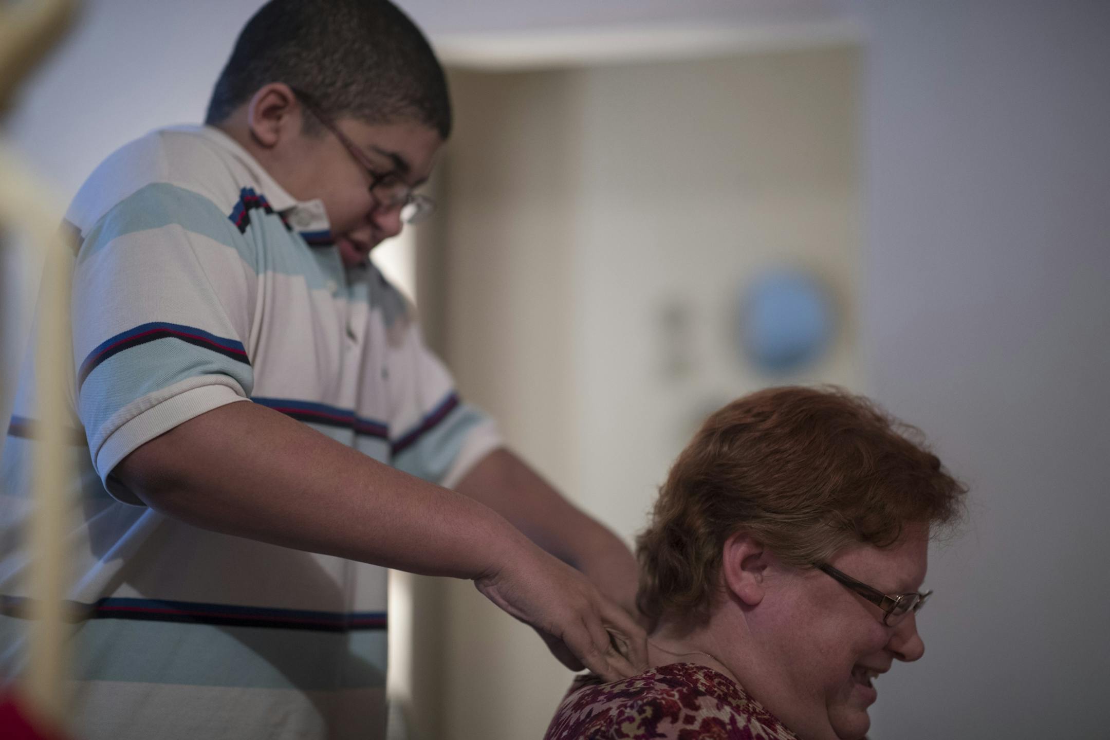 Jordan Mustin give his mom Cora Mustin a neck massage after arriving home from school Thursday December 14, 2017 in Mounds View, MN. Jordan has autism and a history of violent outbursts toward himself and family.