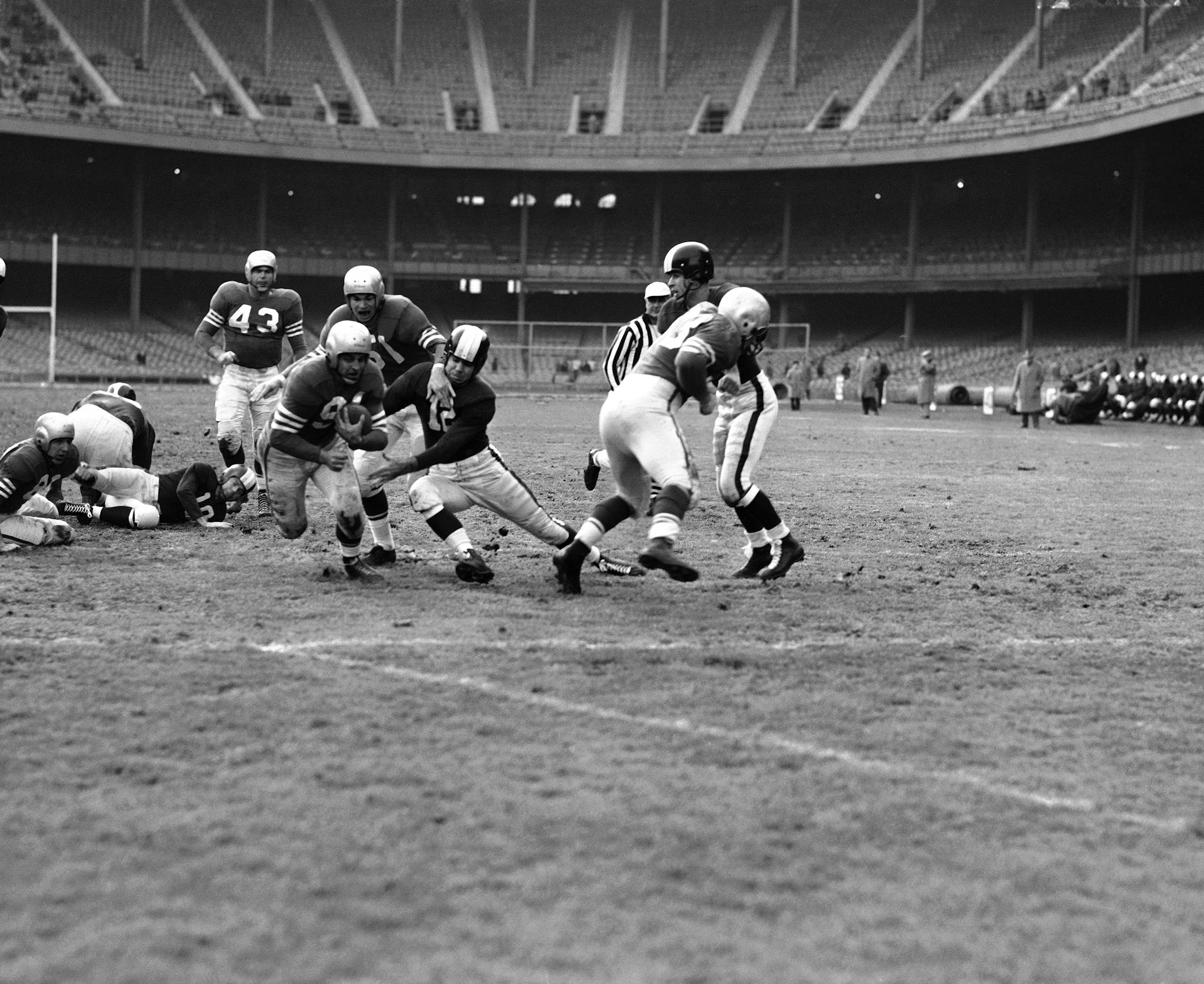 FILE from 1951: John Strzykalski (91), San Francisco 49ers halfback, eludes tackle try of New York's Bruce Alford (12). Giving him a little help against Yank tackler is his teammate, end Gordy Soltau (51). (AP Photo/Harry Harris)