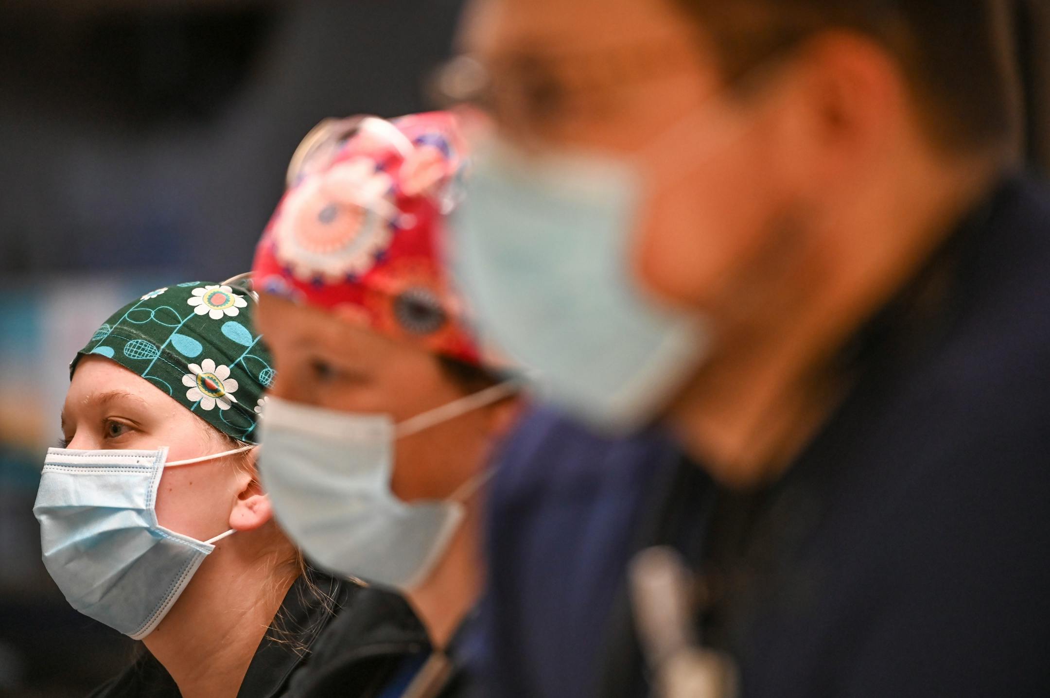 From left, Critical Care nurses Meghan Lund, Amy Peterson and Ethan Pilger listened to nurse manager Lori Wildman as she made a speech as the South 7 ICU marked a year of COVID-19 within its walls.