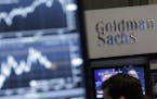 FILE - In this Oct. 16, 2014, file photo, a screen at a trading post on the floor of the New York Stock Exchange is juxtaposed with the Goldman Sachs 