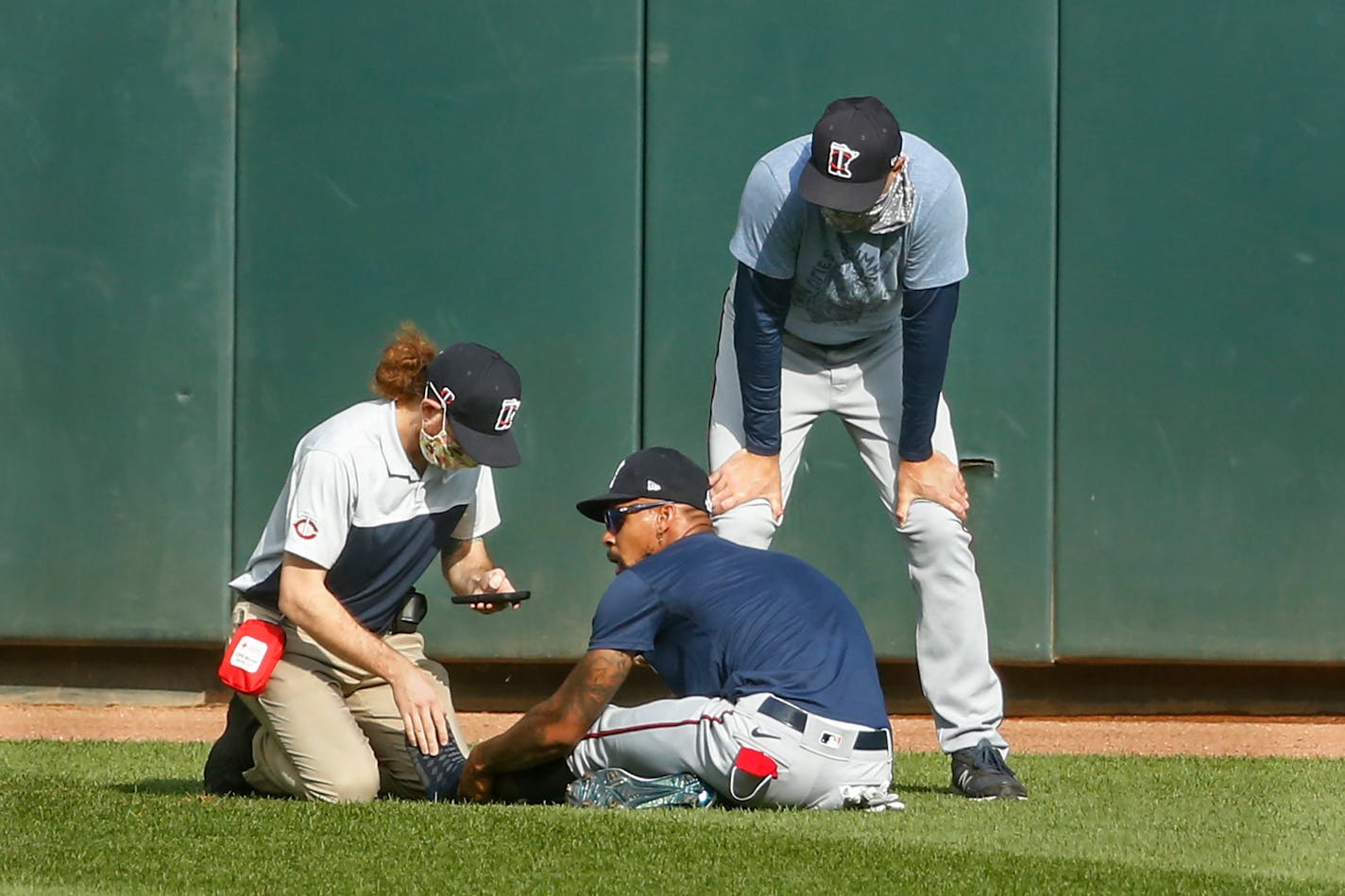 Byron Buxton holds his ankle after he stumbled during an intrasquad game last July. Manager Rocco Baldelli, left, spoke with him be before he left the field on a cart.