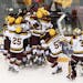 University of Minnesota players swarm Sammy Walker after his second overtime goal over Notre Dame, giving the Gophers a 3-2 win.