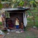 In this April 8, 2013 photo, children look out from their playhouse in a squatter settlement near Tacarigua, Venezuela.