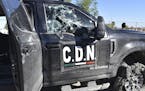 A damaged pick up truck marked with the initials C.D.N., that in Spanish stand for Cartel of the Northeast, stands on the street after a gun battle be