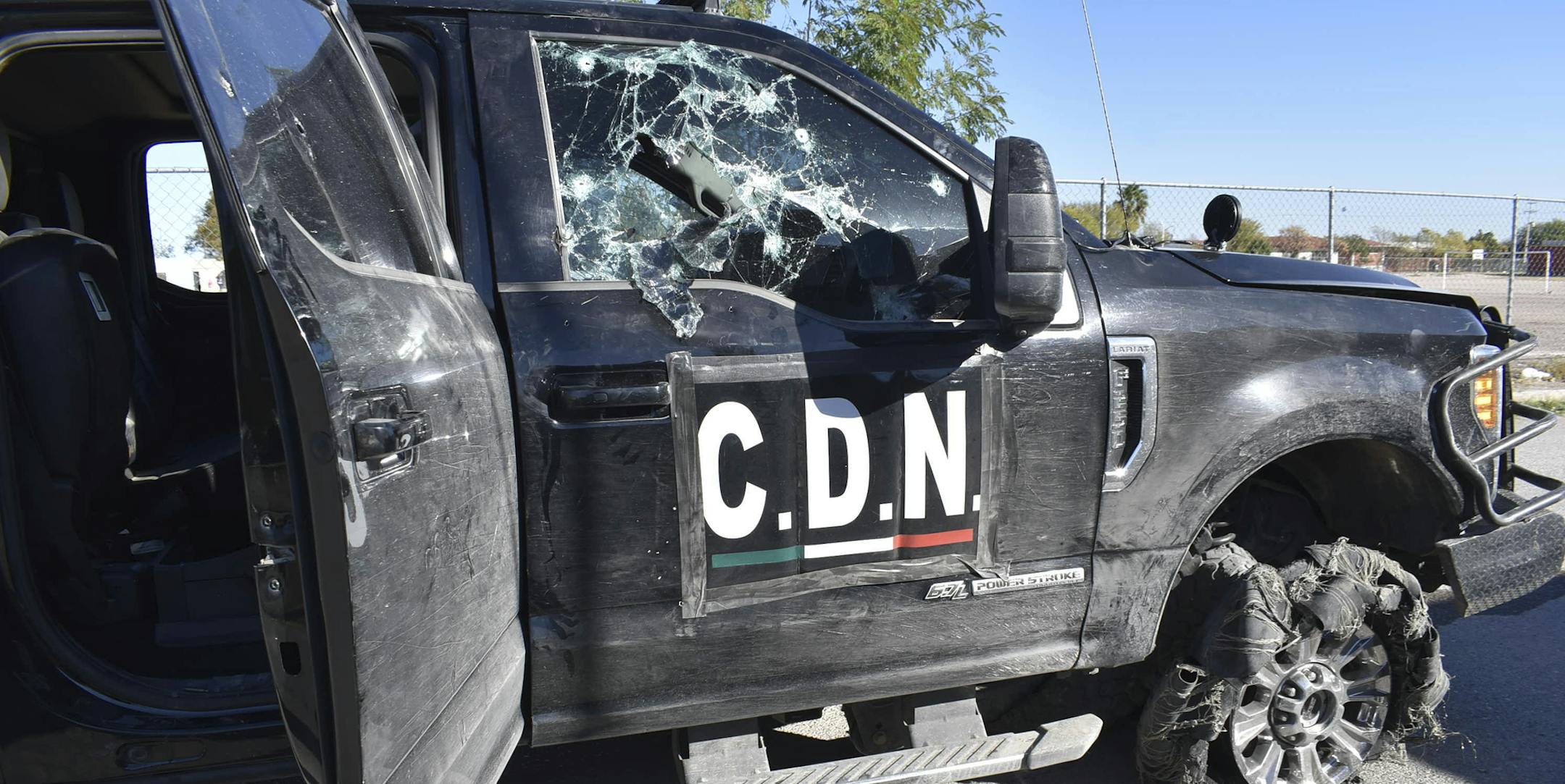 A damaged pick up truck marked with the initials C.D.N., that in Spanish stand for Cartel of the Northeast, stands on the street after a gun battle between Mexican security forces and suspected cartel gunmen, in Villa Union, Mexico, Sunday, Dic. 1, 2019. Mexican security forces on Sunday killed seven more members of a presumed cartel assault force rolled into a town near the Texas border and staged an hour-long attack, officials said, bringing the death toll to at least 21. (AP Photo/Gerardo San