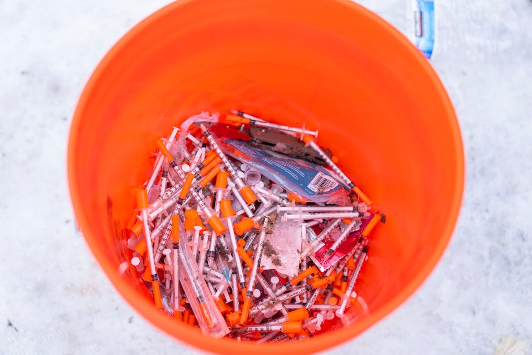 Workers filled a bucket with needles as they took down a homeless encampment in Minneapolis' Cedar-Riverside neighborhood in January 2023.