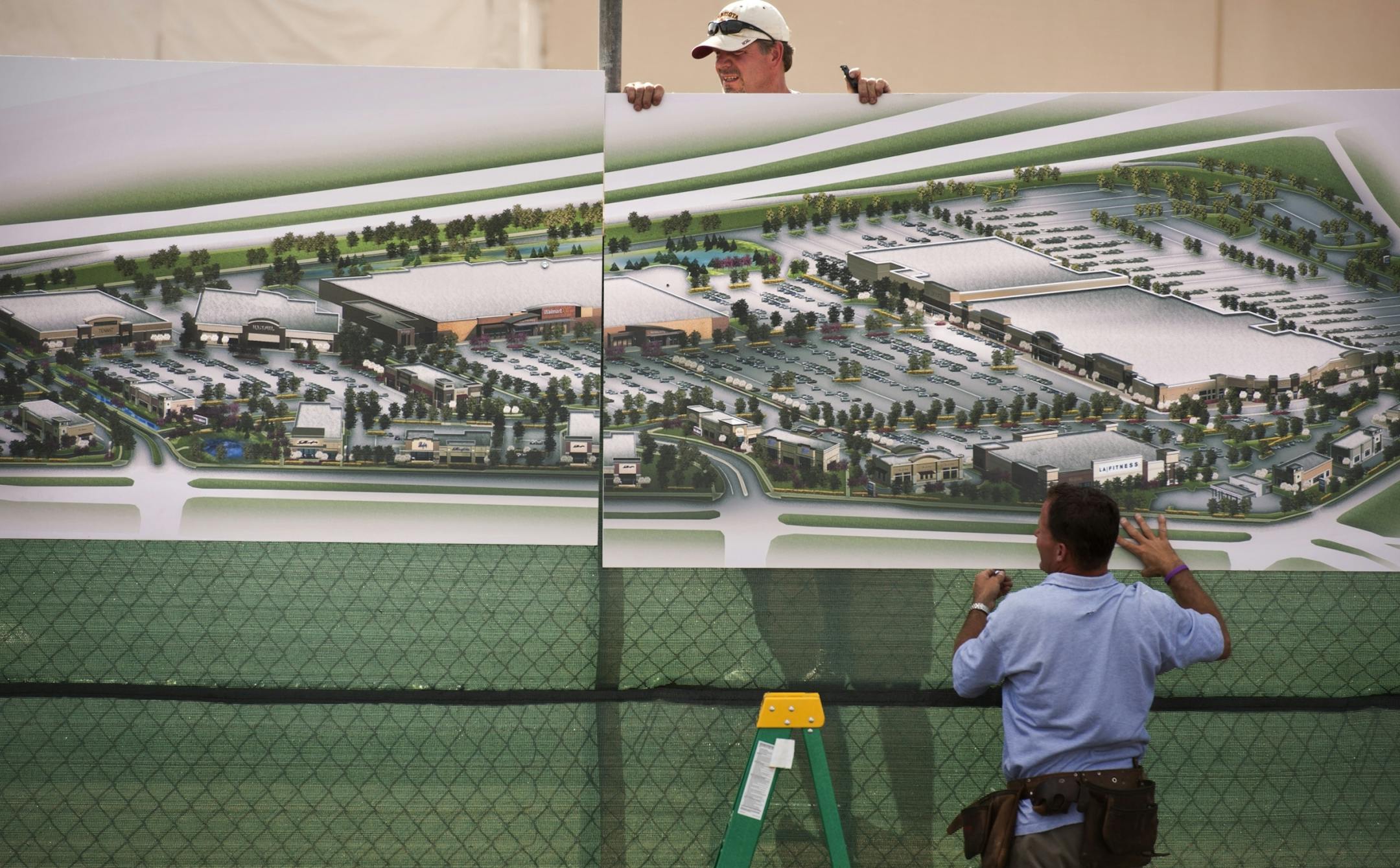 Pete Cote, left, and Scott Kragness of 4Front Media hung signs around the new retail center, showing Wal-Mart in the center. Existing Sears and Kohl's stores also anchor Shingle Creek Crossing, while about 750,000 square feet of the old mall was torn down.