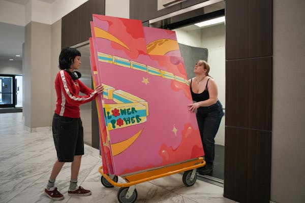 St. Paul Conservatory for Performing Arts students Livia Disney, left, and Freya Wiles wheel painted panels into an elevator for a skyway for installa
