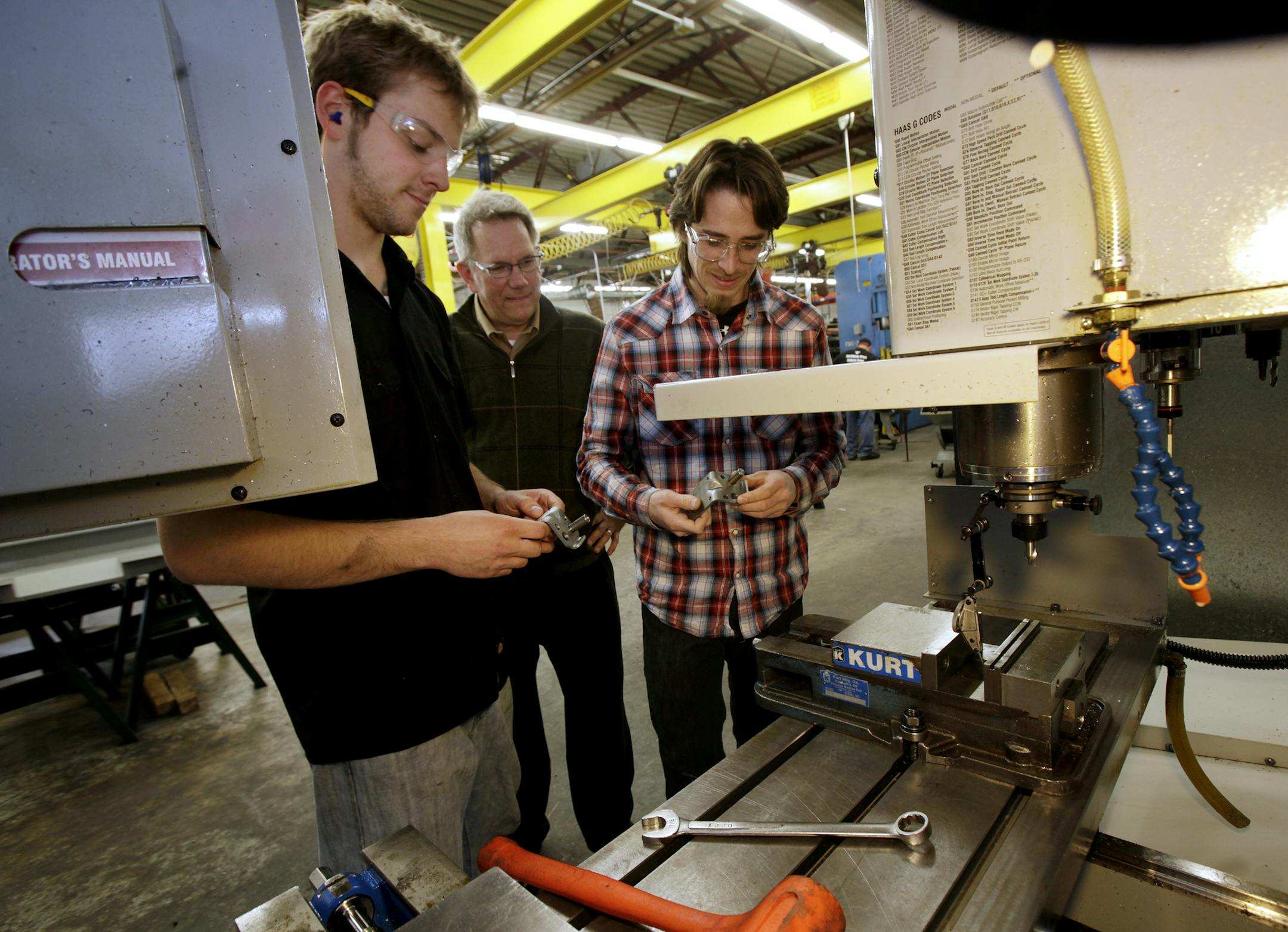 Intern from Dunwoody, Joe Brudzinski, (left), Erick Ajax, co-owner of E.J. Ajax & Sons Inc., and Dunwoody intern Talon Ganz (right) looked over part that they were working on at the.Fridley, MN plant on March 25, 2013. ] JOELKOYAMA&#x201a;&#xc4;&#xa2;joel koyama@startribune.com Ajax at EJ Ajax & Sons in Fridley is hosting a Dunwoody College of Technology Da. They are celebraing the graduation of several employee/ apprentices into full journeyman status. This company is a metal stamper that train