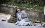 A nun checks her mobile phone as she lies near a victim laid on a ladder following an earthquake in Amatrice Italy, Wednesday, Aug. 24, 2016. The magn