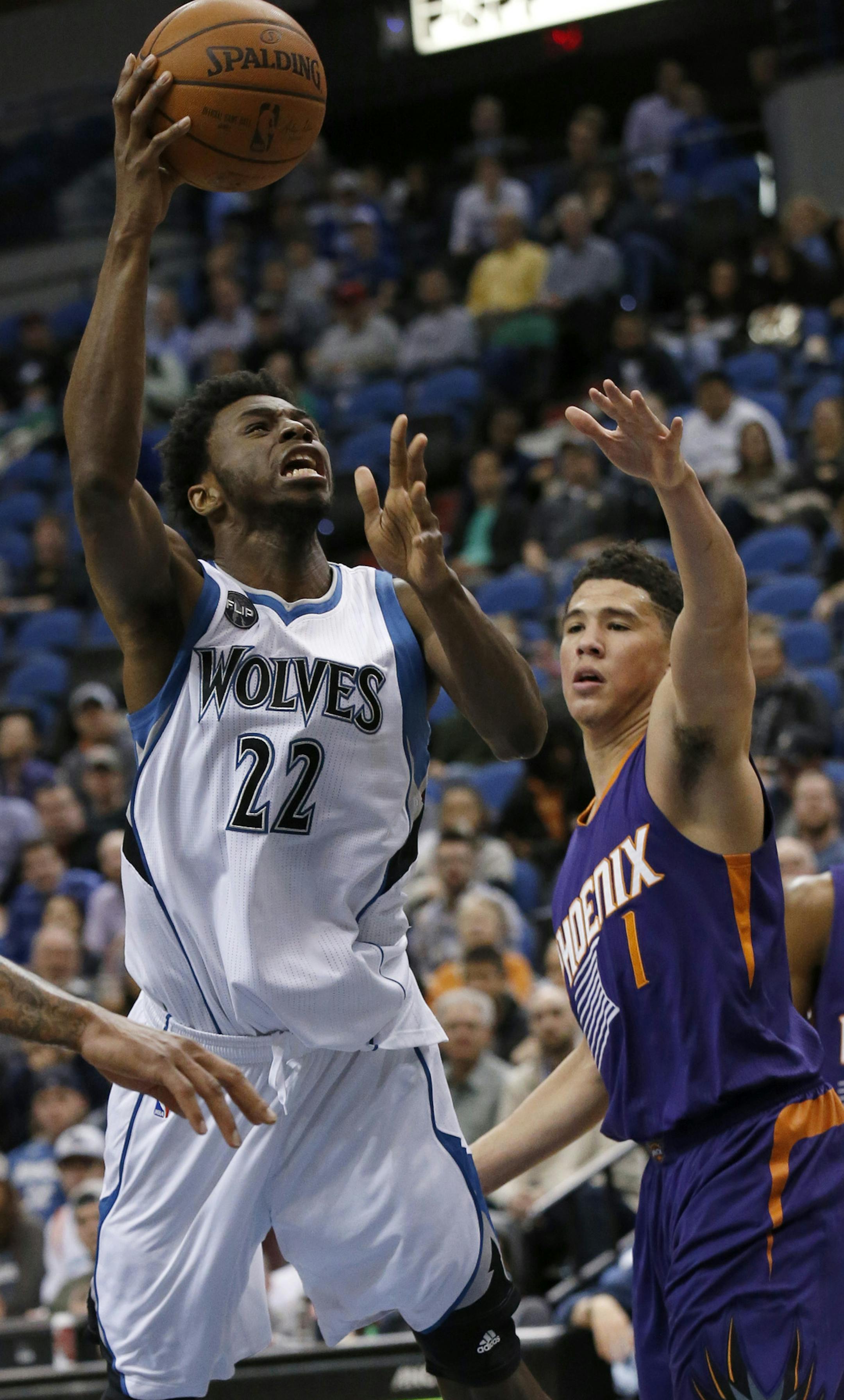 Minnesota Timberwolves guard Andrew Wiggins (22) goes up for a shot over Phoenix Suns guard Devin Booker (1) during the second half of an NBA basketball game in Minneapolis, Monday, March 28, 2016. The Timberwolves won 121-116. (AP Photo/Ann Heisenfelt)