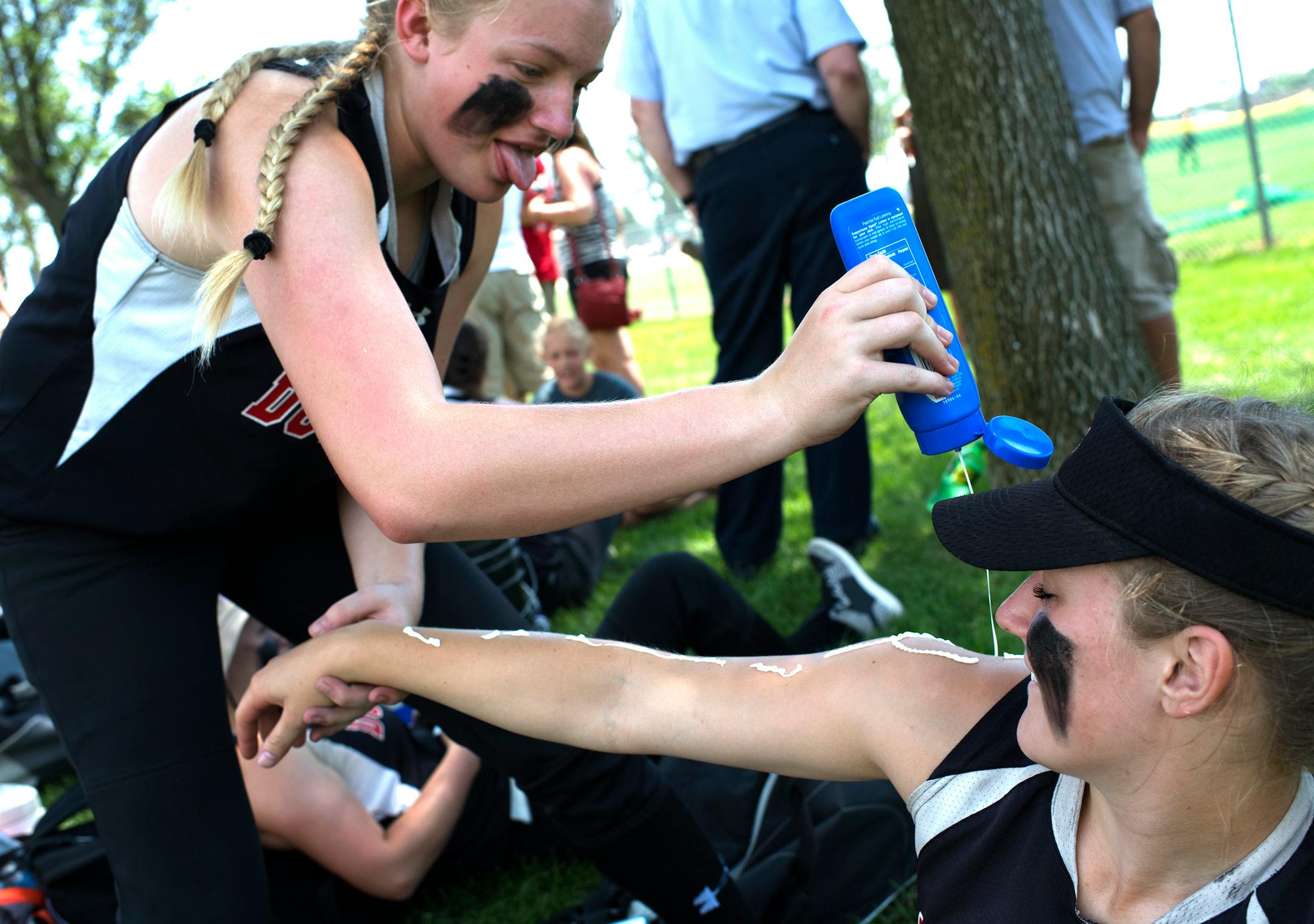 Edgerton/Soutwest Minnesota Christian shortstop Chynna Berning, left, helps pitcher Elizabeth Buckridge apply sunscreen before the 1A State Championship game on Friday at Caswell Park in North Mankato. Temperatures today could reach up to 94 degrees.