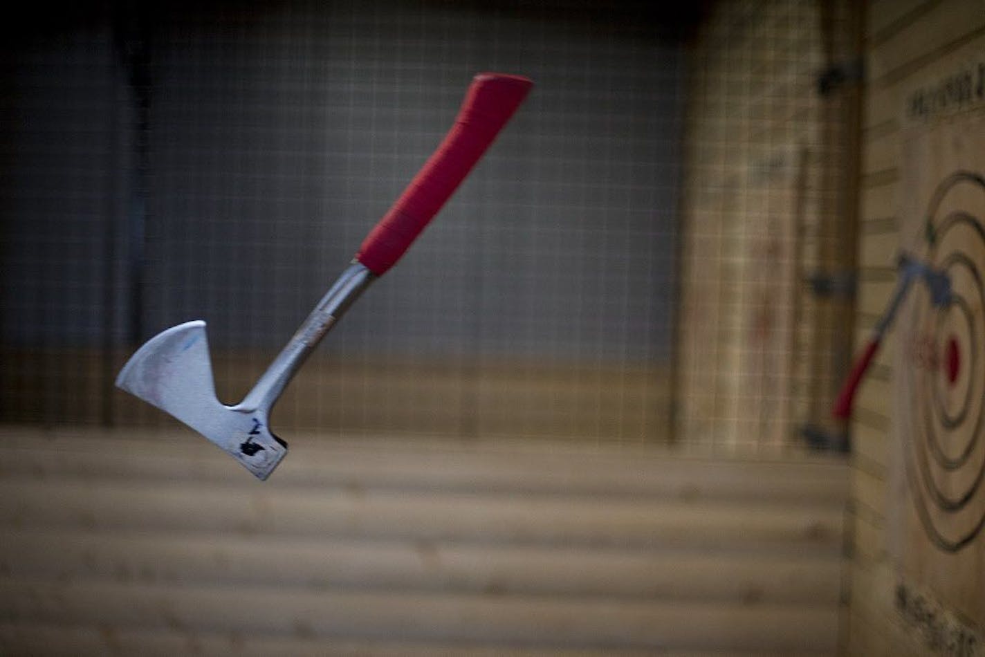 An axe rotates towards the wooden target on the wall.