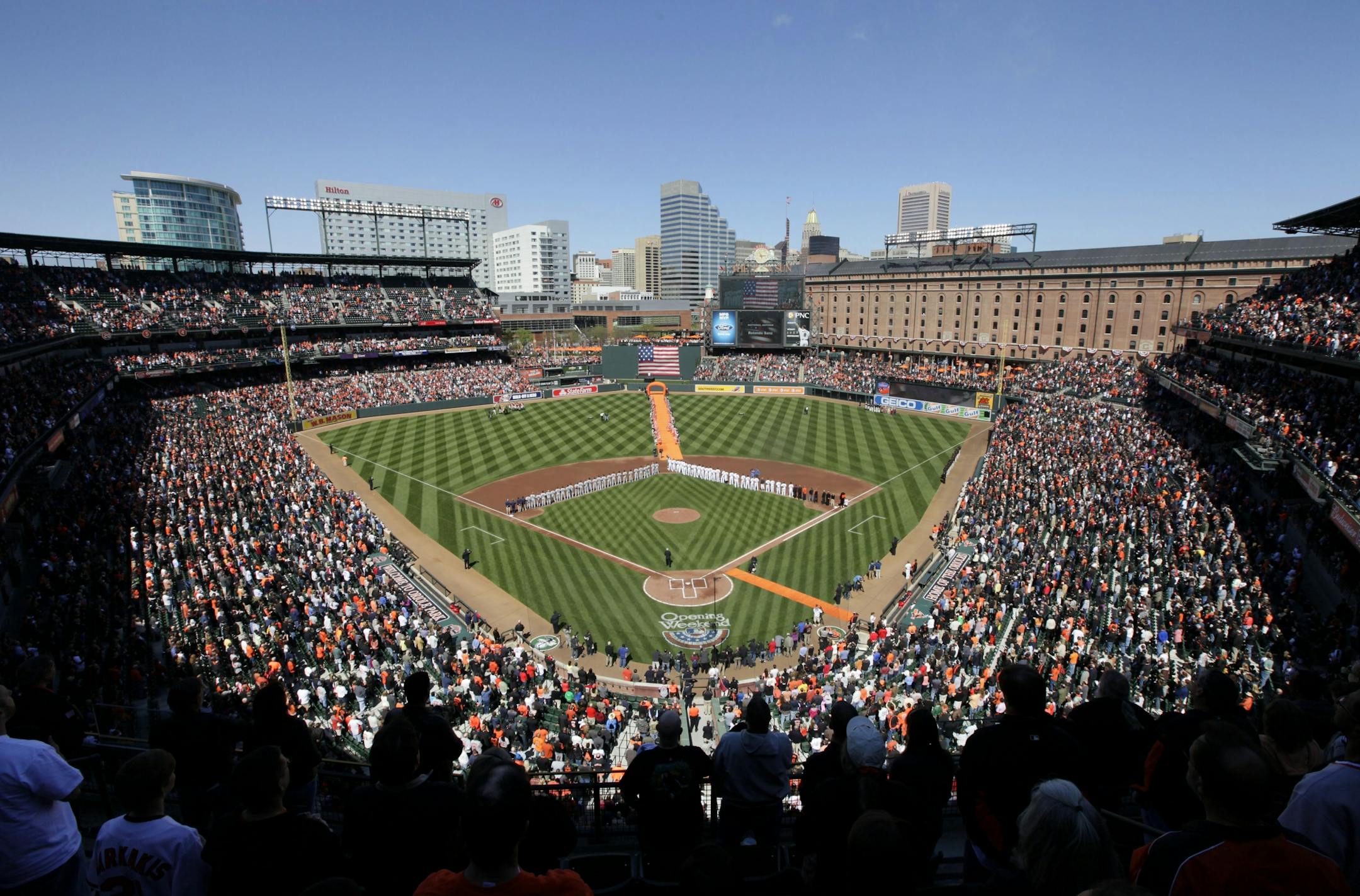 Fans and players stand for the national anthem before the Baltimore Orioles' home opener baseball game against the Minnesota Twins in Baltimore, Friday, April 6, 2012.