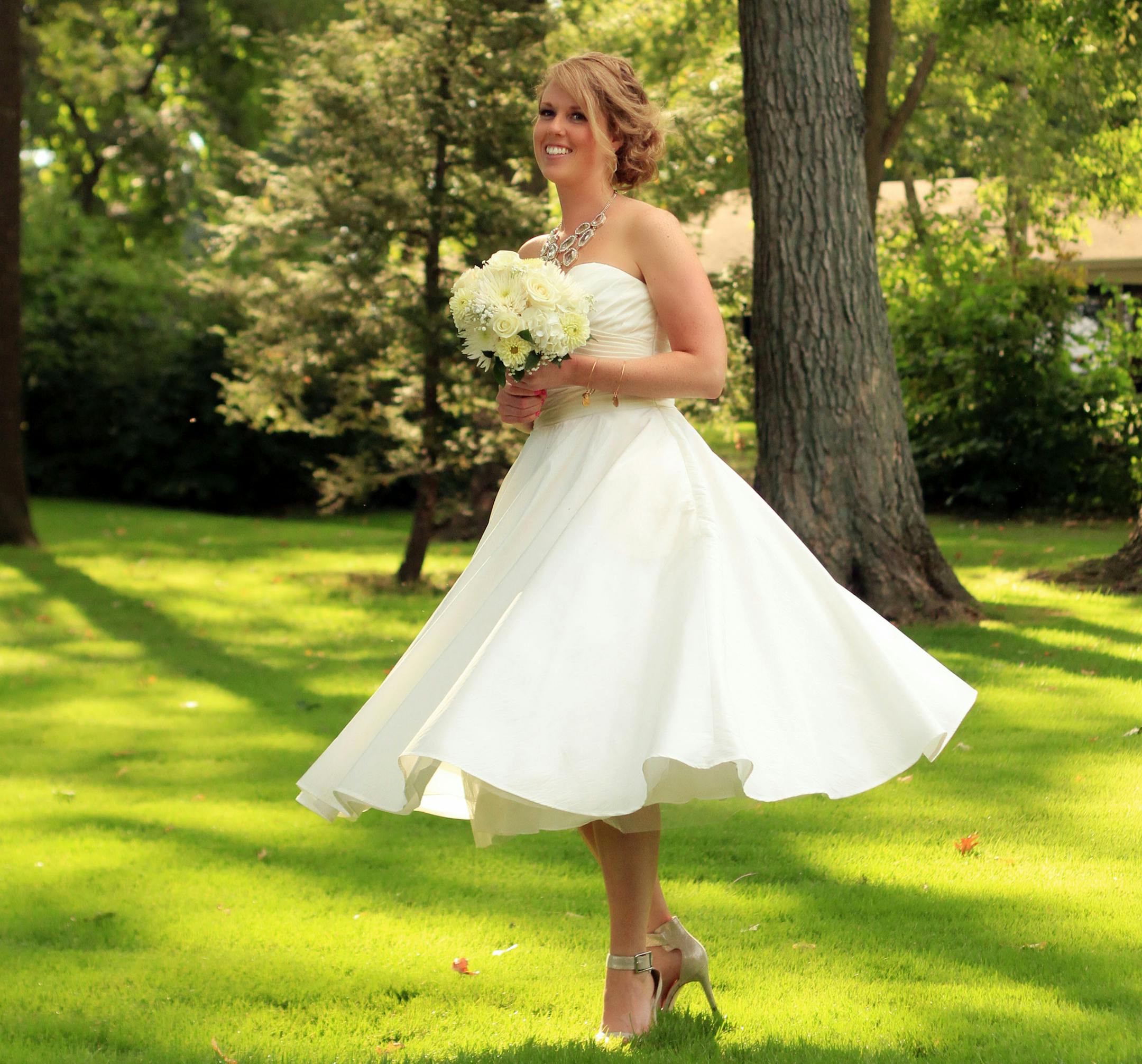In this Sept. 20, 2014 photo released by Alan D. Charles, Helen Bradley, 27, of DePere, Wis., poses on her wedding day at a country club in Madison, Wis. She chose a short gown for three reasons: comfort, affordability and the chance to show off her accessories. (AP Photo/Alan D. Charles)