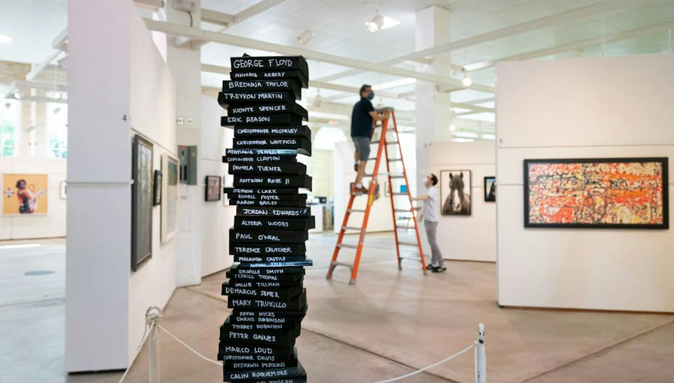 Fair art superintendent Jim Clark and assistant superintendent C.J. Renner adjusted the lighting on this year's exhibits. In the foreground is Tipping Points (Out of Circulation by J. Dan E. Maruska, books on steel frame.