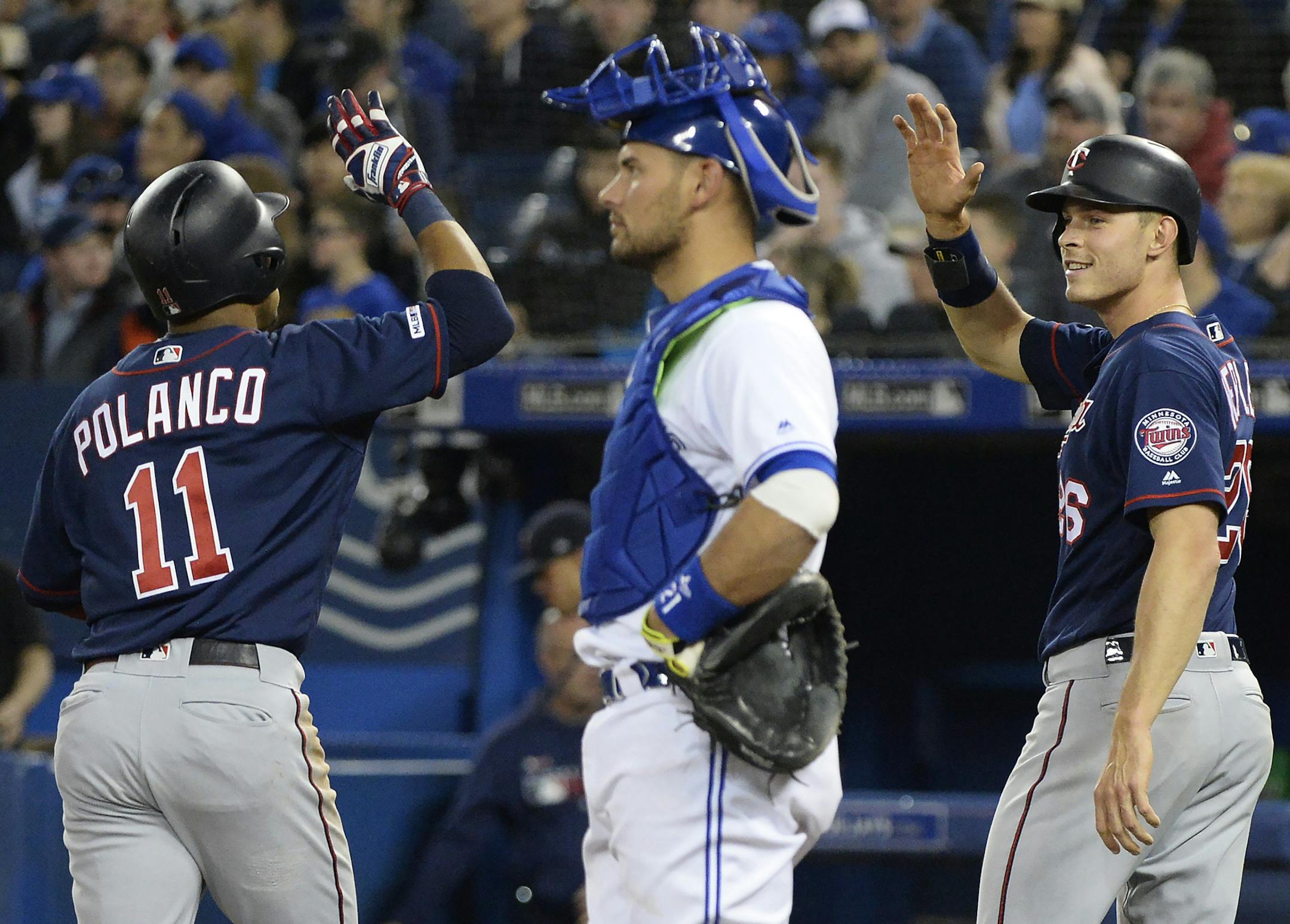 Minnesota Twins' Jorge Polanco (11) celebrates his home run with teammate Max Kepler (26) as Toronto Blue Jays catcher Luke Maile looks on during the second inning of a baseball game, Wednesday, May 8, 2019, in Toronto. (Nathan Denette/The Canadian Press via AP)
