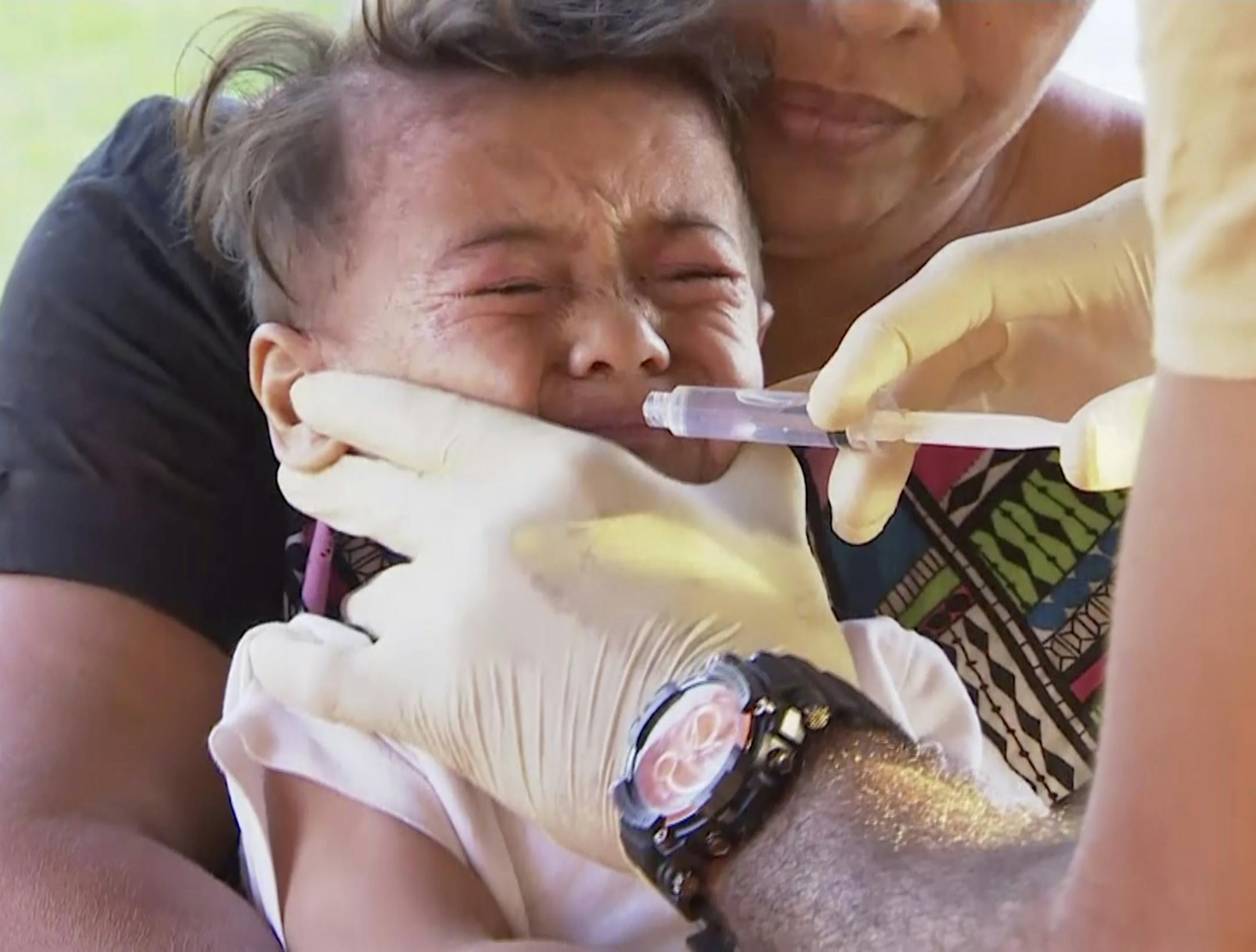 In this November 2019, image from video, a child gets vaccinated at a health clinic in Apia, Samoa. Samoa closed all its schools on Monday, Nov.18, 2019, banned children from public gatherings and mandated that everybody get vaccinated after declaring an emergency due to a measles outbreak. For the past three weeks, the Pacific island nation of 200,000 people has been in the grip of a measles epidemic that has been exacerbated by low immunization rates. (TVNZ via AP) ORG XMIT: TKTT811