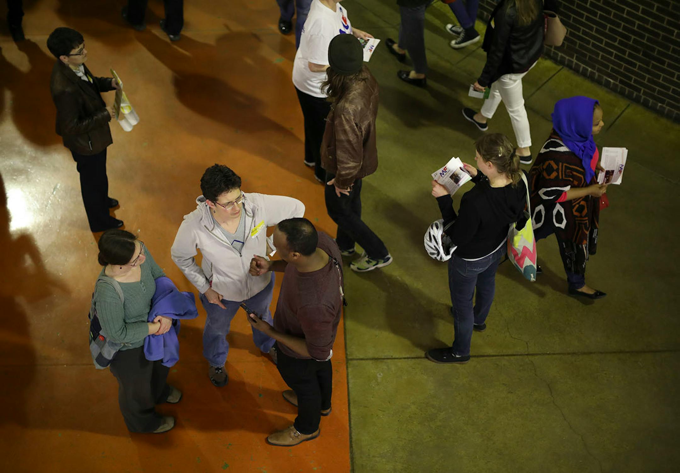 City council candidate Mhamed Farah, center below, talked to caucus attendees as they arrived in the cafeteria at South High School.