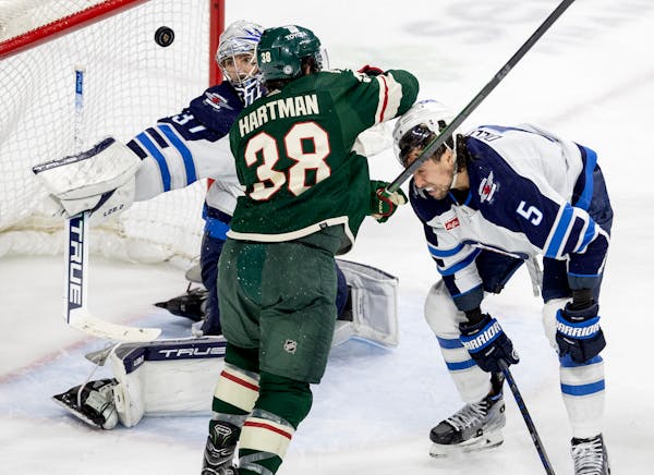 Ryan Hartman (38) of the Minnesota Wild and Brenden Dillon (5) of the Winnipeg Jets tangled in front of Jets goalie Connor Hellebuyck in the third per