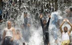 In this 2014 file image, Pakistani youth crowd a water fall in a park to beat the heat in Lahore. Severe heat wave conditions would continue over most