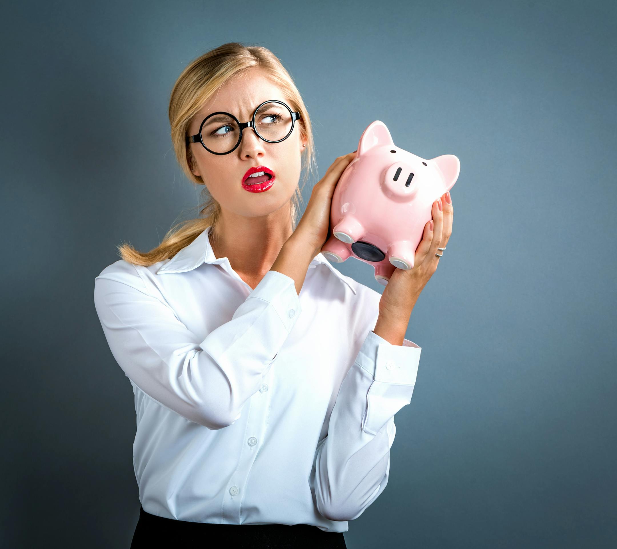 Young woman with a piggy bank on a gray background