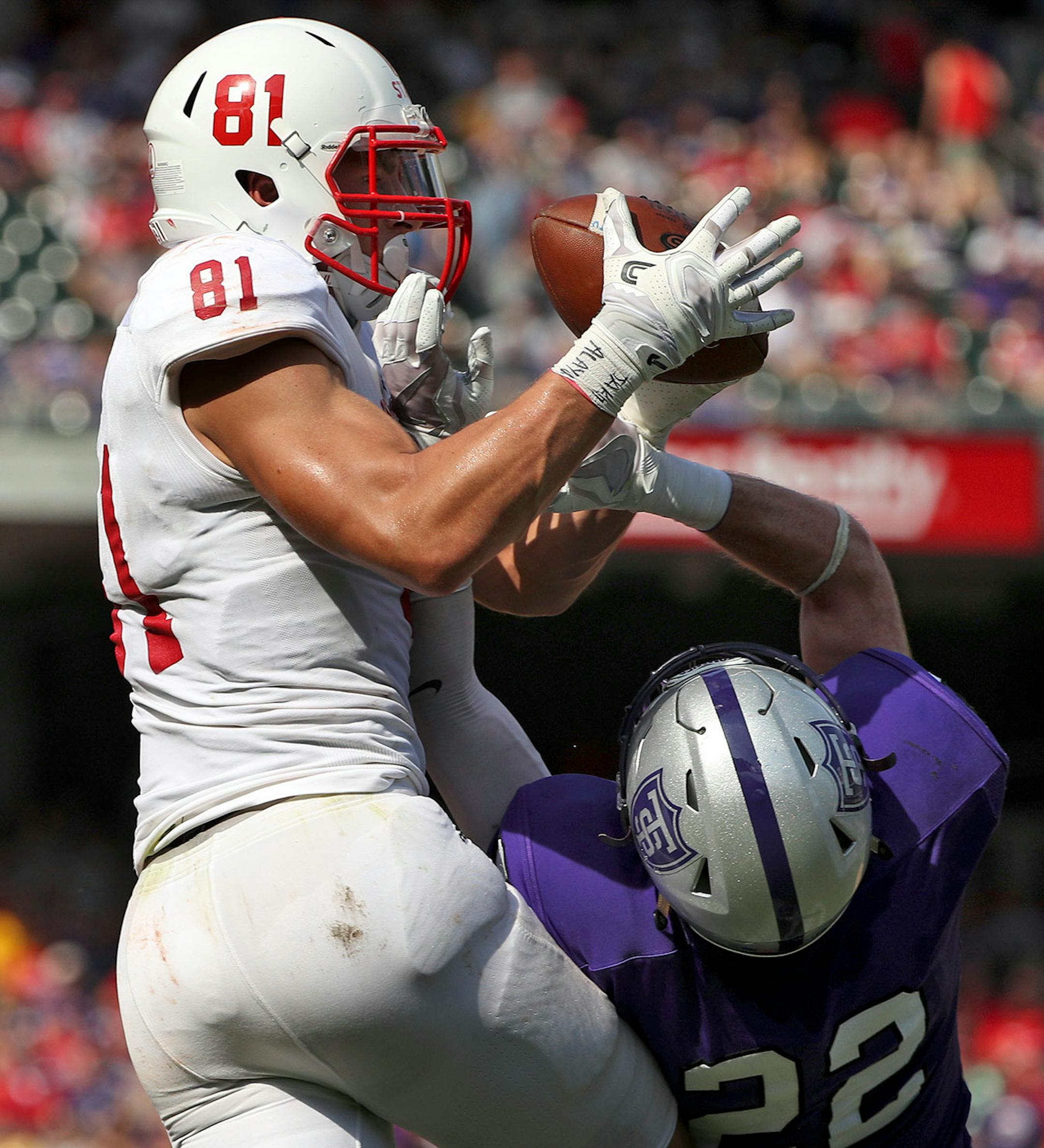 St. John's University tight end Jared Streit (81) leapt to grab a touchdown pass as University of St. Thomas defensive back Mark Dowdle (22) jumped to defend in the first half.